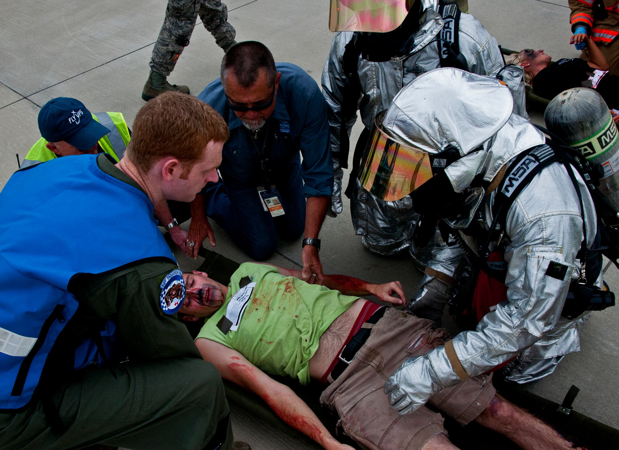 Eglin first responders and Northwest Florida Regional Airport employees secure a victim of a simulated aircraft fire to a stretcher during a mass casualty exercise at the Northwest Florida Regional Airport April 19.  The scenario called for emergency units from Eglin, Okaloosa County and the airport to respond to an aircraft on fire containing more than 40 passengers.  Response, communication and accountability were among many procedures under evaluation at the exercise.  Inside the airport, employees were tested on their response to an influx of friends and family members (of the victims) looking for information about the accident.  The Federal Aviation Administration mandates this type of major accident exercise execution every three years.  (U.S. Air Force photo/Samuel King Jr.)