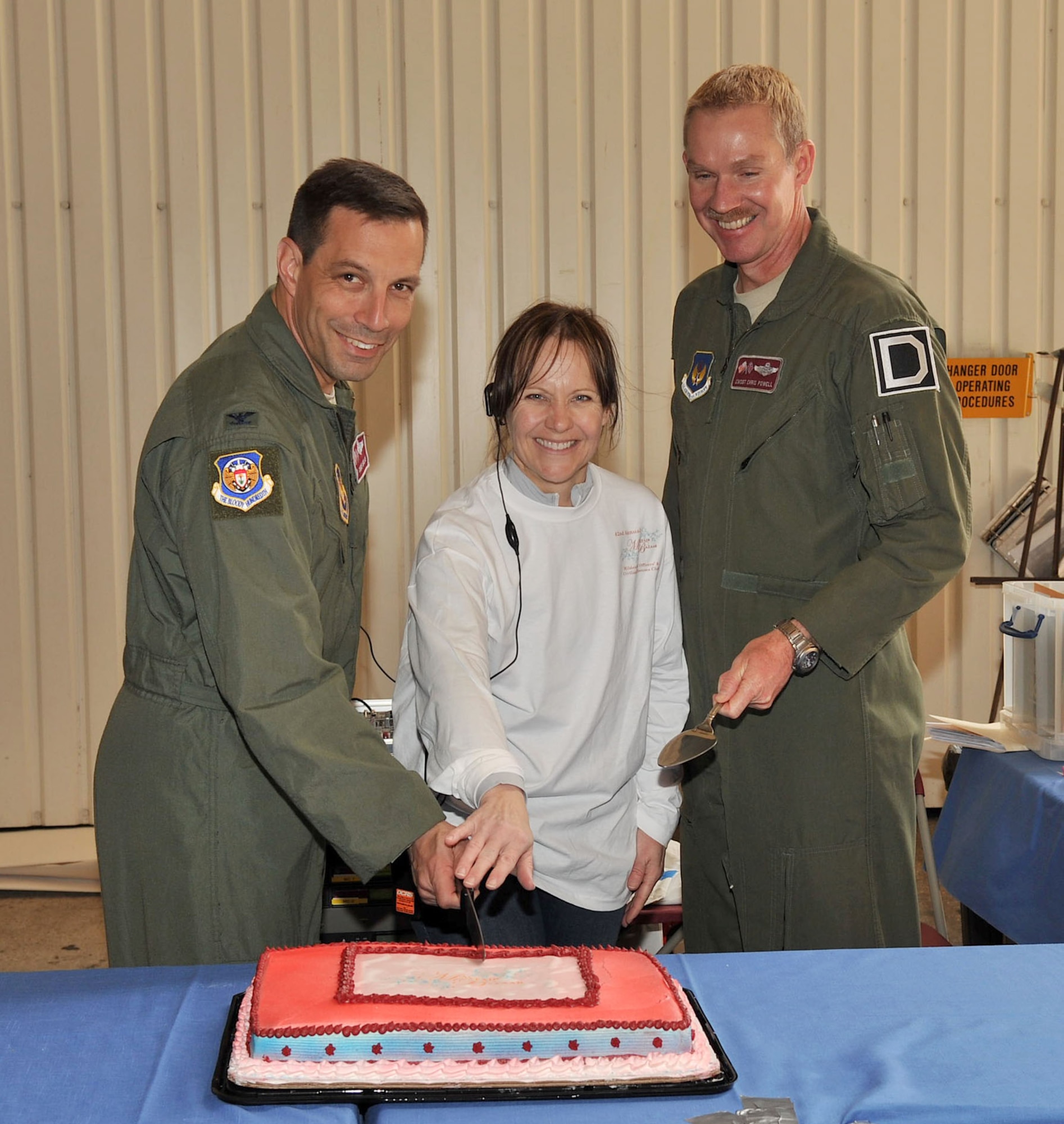 RAF MILDENHALL, England – Col. Christopher Kulas, 100th Air Refueling Wing commander, Barbara Bright, Mayfair Bazaar committee chairperson, and Chief Master Sgt. Christopher Powell, 100th ARW command chief, cut the cake officially kicking off the Mayfair Bazaar event here April 20, 2012. The annual event is open to everyone with access to the base and their guests. (U.S. Air Force photo/Senior Airman Jerilyn Quintanilla)
