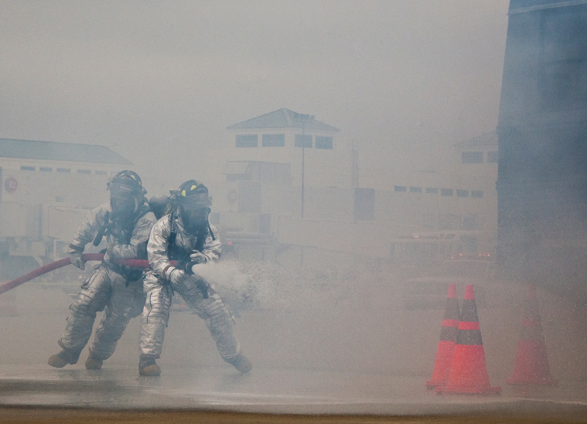 Eglin firefighters move in through the smoke to attack the simulated aircraft fire during a mass casualty exercise at the Northwest Florida Regional Airport April 19.  The scenario called for emergency units from Eglin, Okaloosa County and the airport to respond to an aircraft on fire containing more than 40 passengers.  Response, communication and accountability were among many procedures under evaluation at the exercise.  Inside the airport, employees were tested on their response to an influx of friends and family members looking for information about the accident.  The Federal Aviation Administration mandates this type of major accident exercise execution every three years.  (U.S. Air Force photo/Samuel King Jr.)