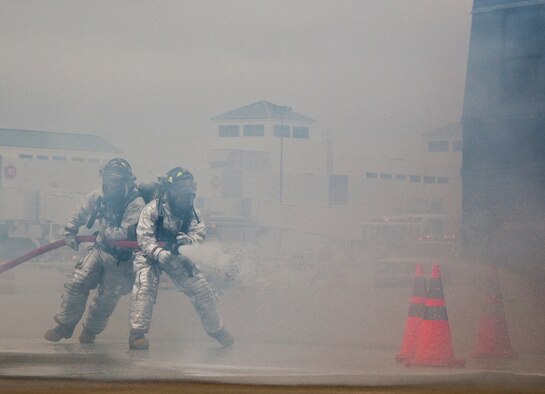 Eglin firefighters move in through the smoke to attack the simulated aircraft fire during a mass casualty exercise at the Northwest Florida Regional Airport April 19.  The scenario called for emergency units from Eglin, Okaloosa County and the airport to respond to an aircraft on fire containing more than 40 passengers.  Response, communication and accountability were among many procedures under evaluation at the exercise.  Inside the airport, employees were tested on their response to an influx of friends and family members looking for information about the accident.  The Federal Aviation Administration mandates this type of major accident exercise execution every three years.  (U.S. Air Force photo/Samuel King Jr.)