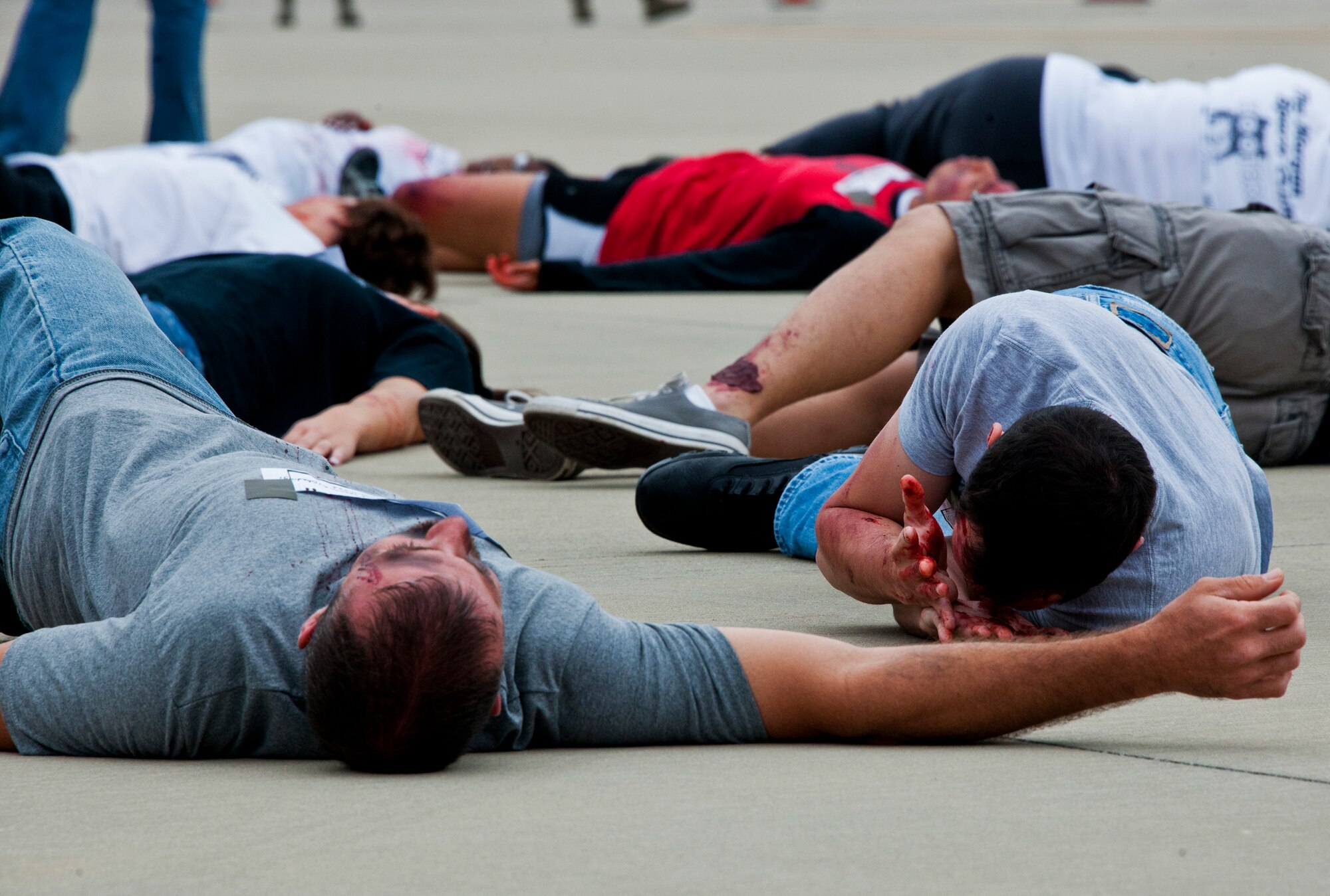 Victims of a simulated aircraft fire writhe on the flightline waiting for help from emergency responders during a mass casualty exercise at the Northwest Florida Regional Airport April 19.  The scenario called for emergency units from Eglin, Okaloosa County and the airport to respond to an aircraft on fire containing more than 40 passengers.  Response, communication and accountability were among many procedures under evaluation at the exercise.  Inside the airport, employees were tested on their response to an influx of friends and family members looking for information about the accident.  The Federal Aviation Administration mandates this type of major accident exercise execution every three years.  (U.S. Air Force photo/Samuel King Jr.)