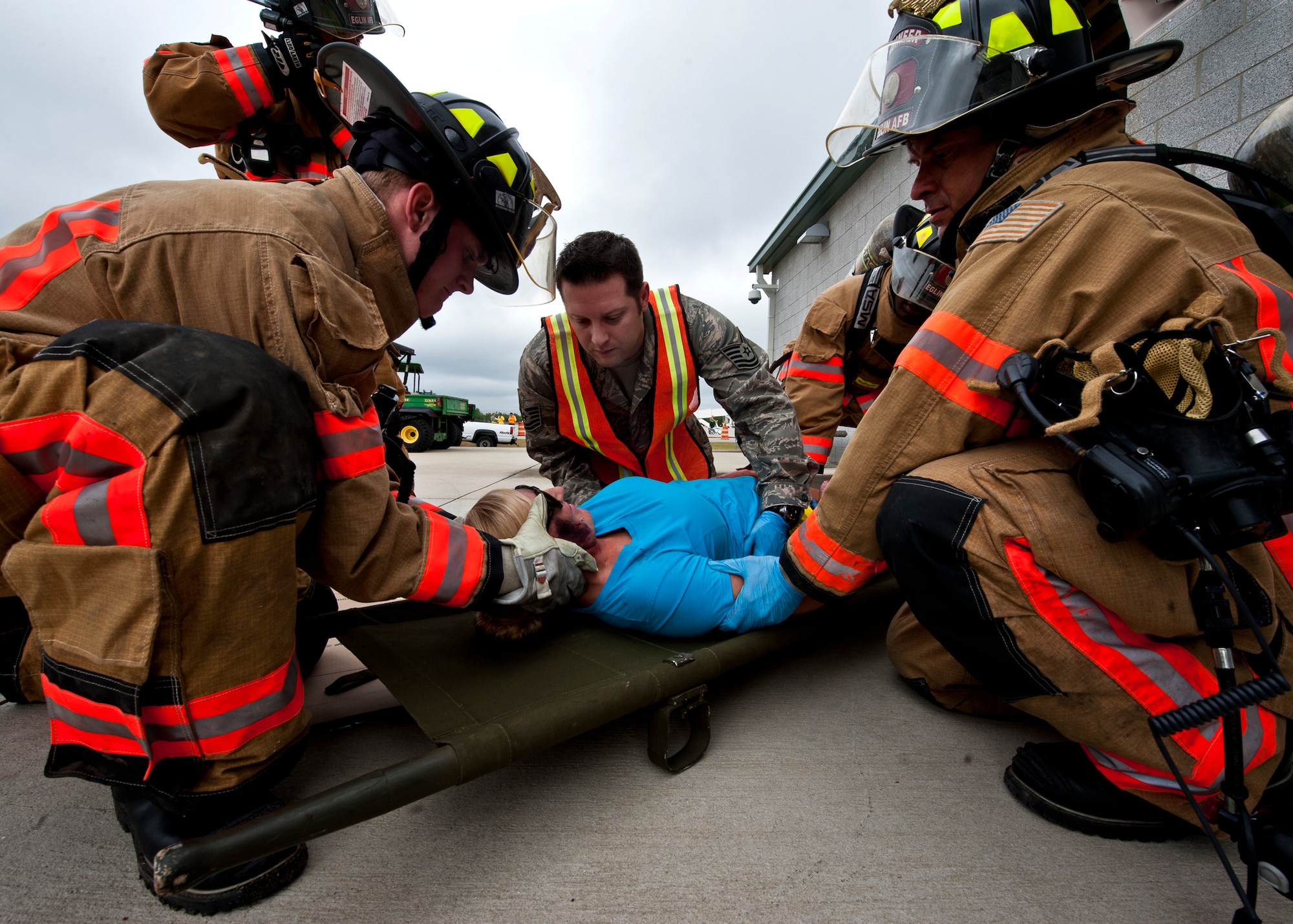 Tech. Sgt. Matthew Scott, an emergency medical technician with the 96th Medical Group, and Eglin firefighters move a victim of a simulated aircraft fire onto a stretcher during a mass casualty exercise at the Northwest Florida Regional Airport April 19.  The scenario called for emergency units from Eglin, Okaloosa County and the airport to respond to an aircraft on fire containing more than 40 passengers.  Response, communication and accountability were among many procedures under evaluation at the exercise.  Inside the airport, employees were tested on their response to an influx of friends and family members looking for information about the accident.  The Federal Aviation Administration mandates this type of major accident exercise execution every three years.  (U.S. Air Force photo/Samuel King Jr.)