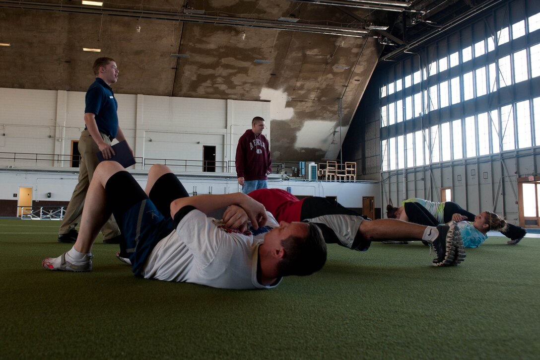 Two-person teams participating in the base’s Amazing Race event perform 100 push ups and 100 sit ups as one of the seven challenges they had to complete before receiving a clue to the next location and challenge at Ellsworth Air Force Base, S.D., April 13, 2012. Twenty teams raced across a three-mile course to complete clues and challenges. (U.S. Air Force photo by Airman 1st Class Zachary Hada/Released)