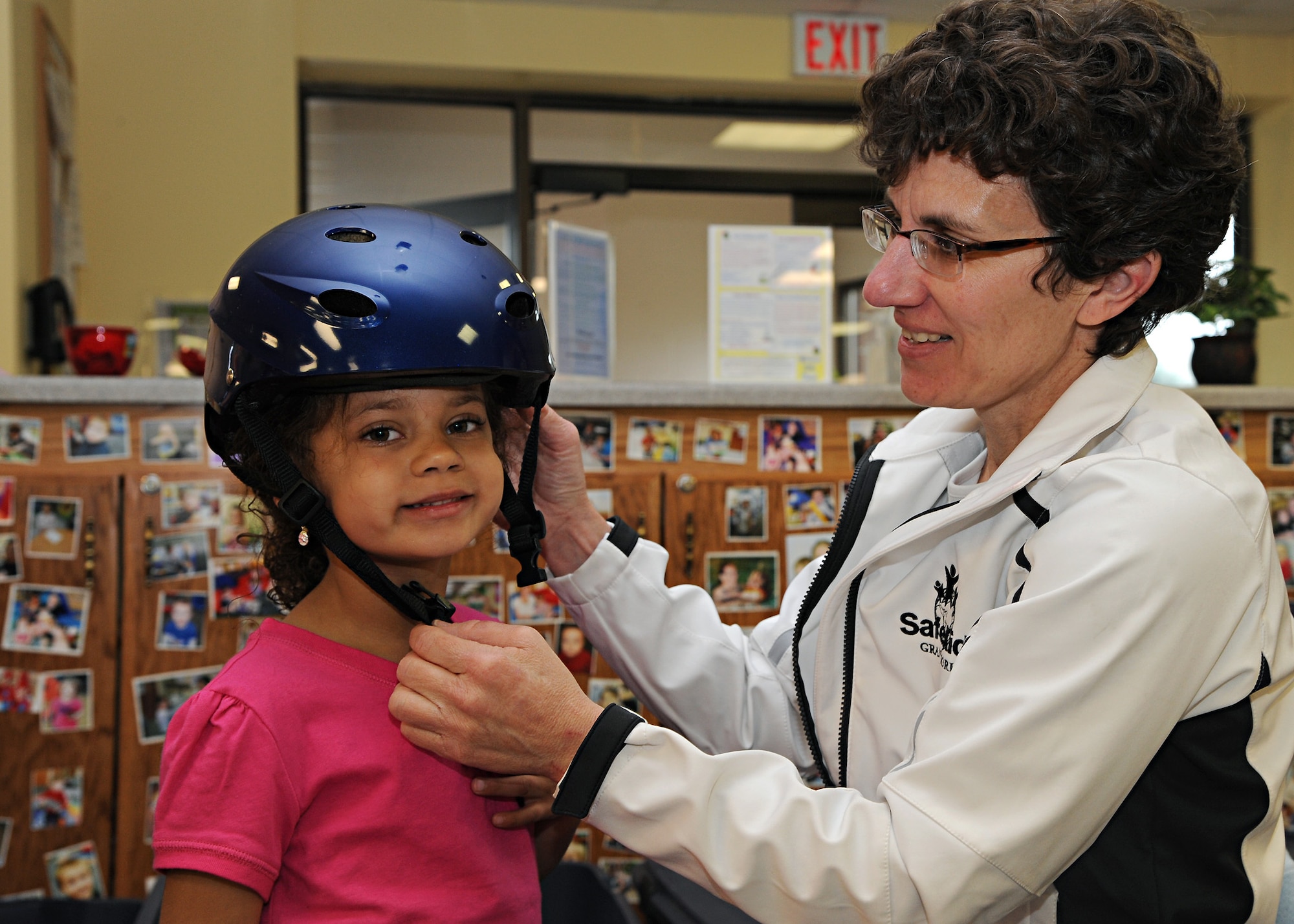 Alyssia Murphy (left), daughter of Tech. Sgt. Kevin Murphy of the 319th Civil Engineer Squadron, smiles while Patty Olsen (right), sports coordinator of Safe Kids Grand Forks, fits her for a helmet on April 18, 2012, on Grand Forks Air Force Base, N.D.  Safe Kids is a nationwide network of organizations working to prevent unintentional childhood injury which is the leading cause of death and disability for children ages 1 to 14. (U.S. Air Force photo by Senior Airman Amber Bennett)