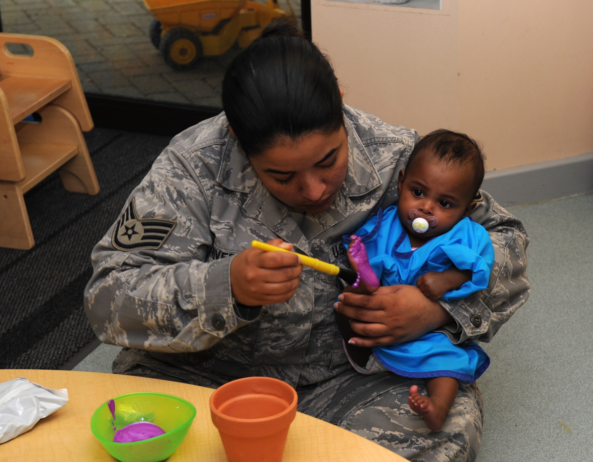 RAF MILDENHALL, England – Staff Sgt. Winellia Rivera, 100th Operations Support Squadron, paints her daughter Lianie’s foot to decorate a pot during an Earth Day parent involvement project at the RAF Mildenhall Child Development Center April 19, 2012. Parents and their children also planted various seeds in celebration of Earth Day. (U.S. Air Force photo/Senior Airman Rachel Waller)