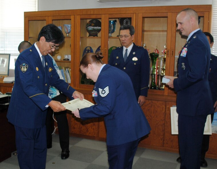Chief Tatsuhiko Toguchi, Okinawa Prefectural Police Okinawa Police Station chief, presents a letter of appreciation to U.S. Air Force Tech. Sgt. Shannon Williams, 18th Security Forces Squadron NCO in charge of investigations, April 18, 2012, in Okinawa, Japan. Williams and U.S. Air Force Lt. Col. John Grimm, 18th SFS commander (right), were presented letters and mementos for their contributions toward fostering the 18th SFS and Okinawa Police relationship. (Courtesy photo)