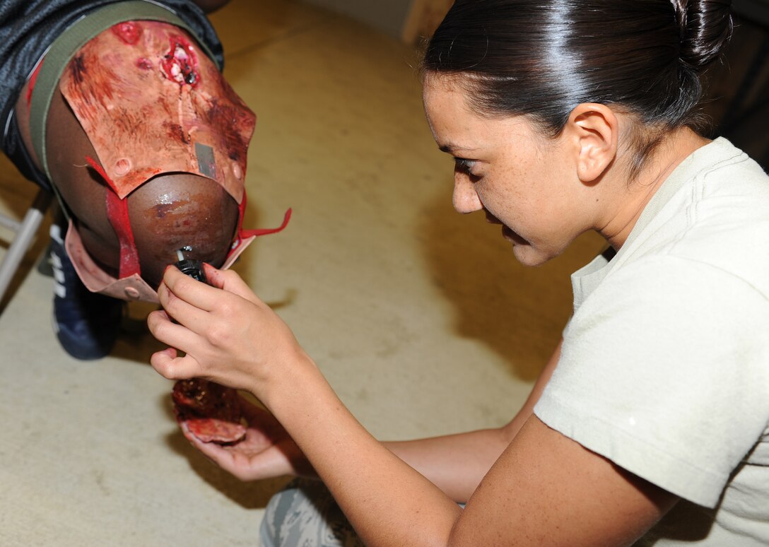 U.S. Air Force Airman 1st Class Francia Bienvenue, 633rd Aerospace Medicine Squadron aerospace and operational physiology technician, applies artificial wounds to A1C Dwayne Campbell, 633rd Dental Squadron dental assistant, during a phase II operational readiness exercise at Langley Air Force Base, Va., April 19, 2012. The ORE was designed to test Airmen across the base in their ability to operate in a deployed environment. (U.S. Air Force photo by Airman 1st Class Teresa Cleveland/Released)