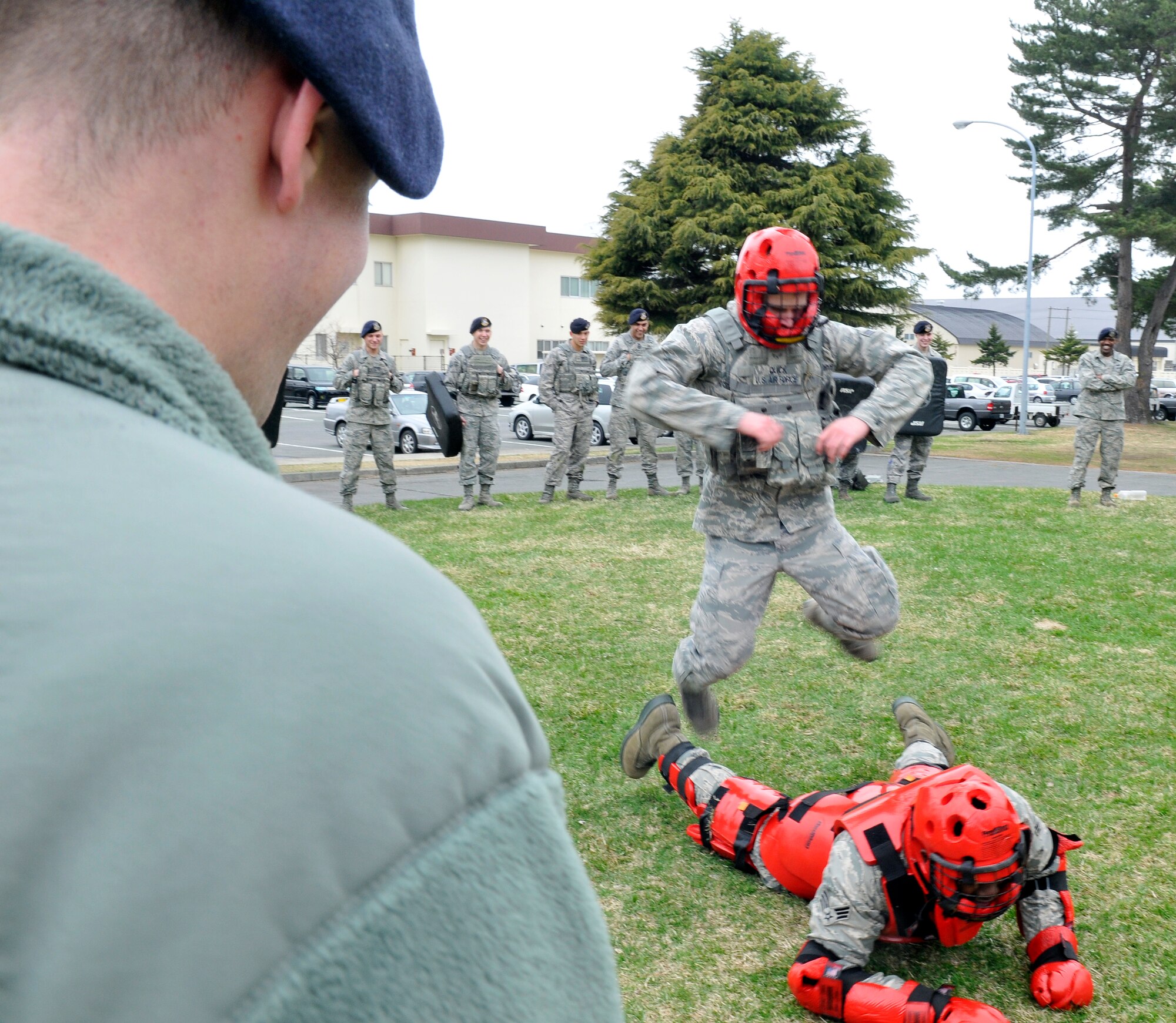 U.S. Air Force Airman 1st Class Marc Quick pounces on Senior Airman Brian Childress during baton training April 19, 2012 at Misawa Air Base, Japan. After Airmen subdue an assailant they must keep positive control by holding them down until help arrives. Baton training teaches Airmen the appropriate way to subdue an assailant. The Airman, acting as the assailant, is protected from serious harm while wearing the red man suit.  Both Airmen are 35th Security Forces Squadron patrolmen. (U.S. Air Force photo by Tech. Sgt. Phillip Butterfield/Released) 