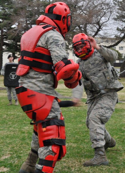 U.S. Air Force Senior Airman Brian Childress, left, while wearing a red man suit, is hit in the thigh with a training baton by Airman 1st Class Kevin Jimenez during baton training April 19, 2012 at Misawa Air Base, Japan. Baton training teaches Airmen how to subdue an assailant while maintaining control. Both Airmen are 35th Security Forces Squadron patrolmen. (U.S. Air Force photo/Tech. Sgt. Phillip Butterfield) 
