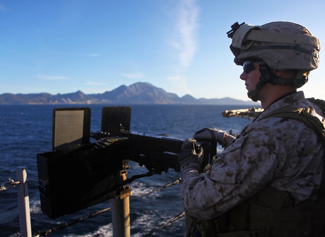 USS NEW YORK - Cpl. Phil Pelletier, a machine gunner with Weapons Company, Battalion Landing Team 1st Battalion, 2nd Marine Regiment, 24th Marine Expeditionary Unit, stands behind an M-2 50 cal. heavy machine gun providing security for the ship as she passes through the Straits of Gibraltar, April 20, 2012. The 24th MEU is currently deployed with the Navy's Iwo Jima Amphibious Ready Group as a theater reserve and crisis response force capable of a variety of missions from full-scale combat operations to humanitarian assistance and disaster relief. (Official Marine Corps Photo by Cpl. Michael Petersheim)