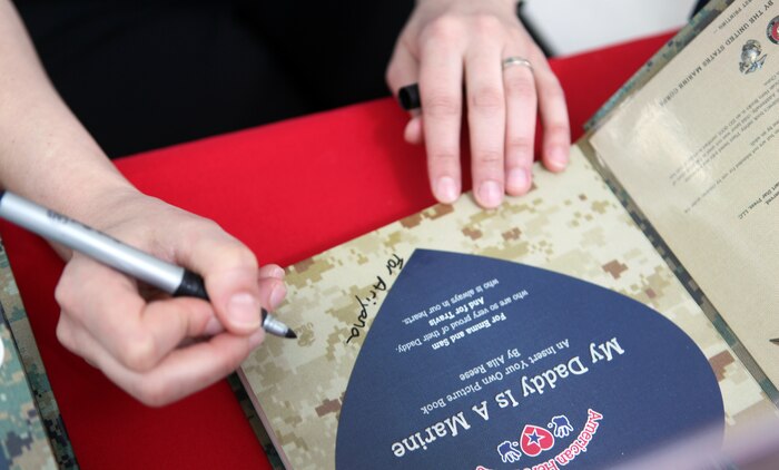 Alia Reese, wife of Maj. Travis Reese, the plans officer for 2nd Marine Logistics Group, signs a book at the Marine Corps Exchange aboard Camp Lejeune, N.C., April 21, 2012. The book is titled “My Daddy is a Marine,” and it teaches young children about the Marine Corps.  It doubles as a photo album, in which children can place pictures of their parents and update it as the years roll by.