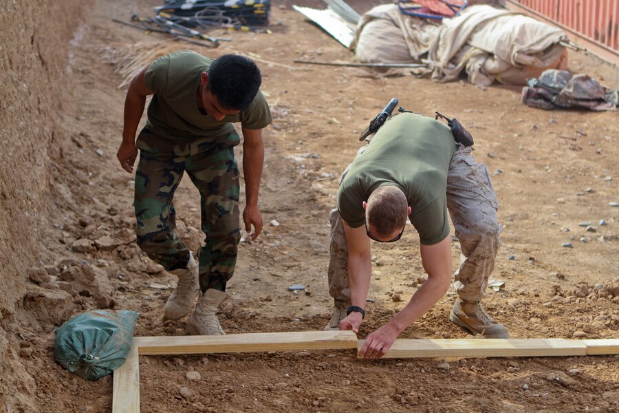 FORWARD OPERATING BASE GERONIMO – Afghan National Army 1st Sgt. Mubarak, the operations first sergeant with 1st Kandak, 1st Brigade, 215th Corps, and Capt. Stephen Walker, the operations advisor with the Embedded Training Team, 2nd Battalion, 6th Marine Regiment, finish forming the perimeter of a terrain model, April 21, 2012. The Kandak staff asked Walker to help build the model for briefings in future operations. A terrain model is a 3-D map that outlines roads and other major geographical features.