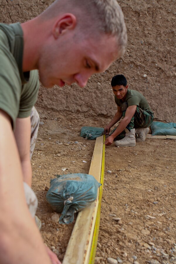 FORWARD OPERATING BASE GERONIMO – Captain Stephen Walker, the operations advisor with the Embedded Training Team, 2nd Battalion, 6th Marine Regiment, measures a grid system for a terrain model with Afghan National Army 1st Sgt. Mubarak, operations first sergeant, 1st Kandak, 1st Brigade, 215th Corps, April 21, 2012. The kandak staff asked Walker to build the terrain model to help with future operations.
