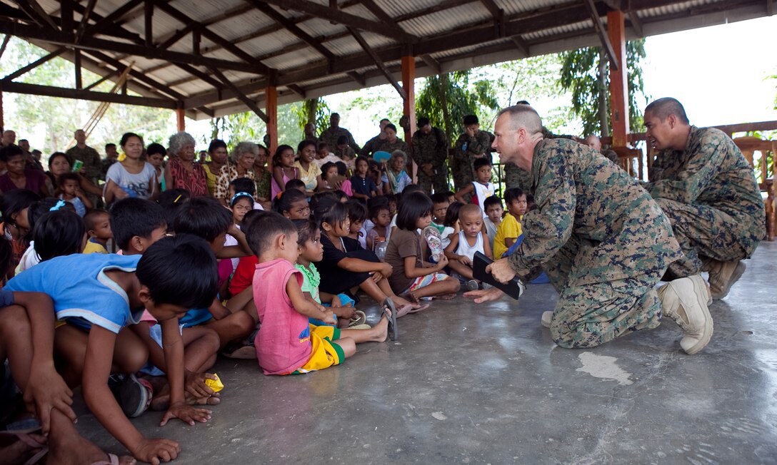 U.S. Navy Lt. Gary W. Foshee (second from right), command chaplain, Combat Logistics Battalion 3, Marine Corps Base Hawaii, tells a bible story to Santa Juliana villagers during a worship service held in the local multipurpose room, April 22. Together members of the village, Armed Forces of the Philippines and U.S. service members repaired two water pumps, hung tire swings in common areas, renovated the local schoolhouse and donated books and school supplies to children in need during Exercise Balikatan 2012. Balikatan, which means "shoulder to shoulder" in Filipino, is an annual training event aimed at improving combined planning, combat readiness, humanitarian assistance and interoperability between the Armed Forces of the Philippines and United States.