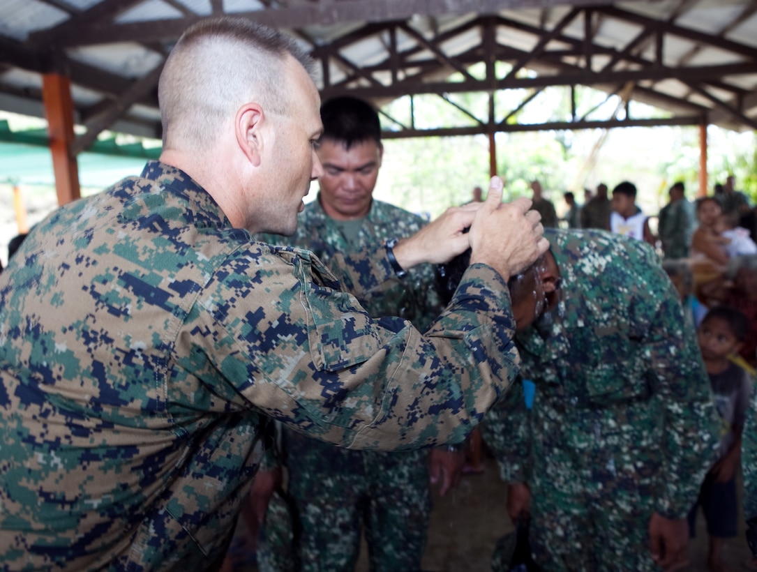 U.S. Navy Lt. Gary W. Foshee, command chaplain, Combat Logistics Battalion 3, Marine Corps Base Hawaii, baptizes members of the Philippine Marine Corps during a worship service held in the local multipurpose room April 22. Together villagers, Armed Forces of the Philippines and U.S. service members repaired two water pumps, hung tire swings in common areas, renovated the local schoolhouse and donated books and school supplies to children in need during Exercise Balikatan 2012. Balikatan, which means "shoulder to shoulder" in Filipino, is an annual training event aimed at improving combined planning, combat readiness, humanitarian assistance and interoperability between the Armed Forces of the Philippines and United States.