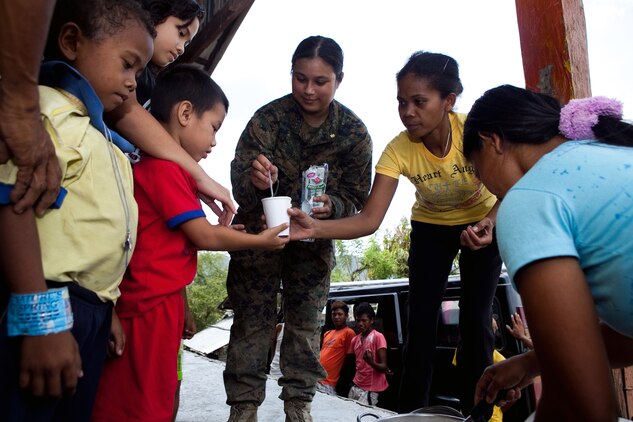 U.S. Navy Petty Officer 1st Class Heidebelle Queddeng, field medical corpsman, Combat Logistics Battalion 3, Marine Corps Base Hawaii, helps serve a community meal to Santa Juliana villagers in the local multi-purpose room April 22. Together villagers, Armed Forces of the Philippines and U.S. service members repaired two water pumps, hung tire swings in common areas, renovated the local schoolhouse and donated books and school supplies to children in need during Exercise Balikatan 2012. Balikatan, which means "shoulder to shoulder" in Filipino, is an annual training event aimed at improving combined planning, combat readiness, humanitarian assistance and interoperability between the Armed Forces of the Philippines and United States.