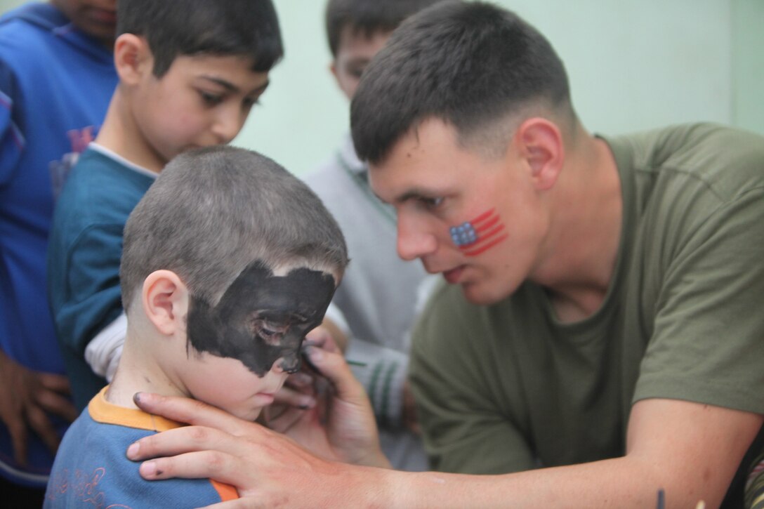 Sgt. Jonathan Davis a reconnaissance Marine with the ground command element, Black Sea Rotational Force 12, paints the face of a young boy from a local orphanage while volunteering in Constanta, Romania, April 22. The Marines and sailors of BSRF 12 worked with Hands Across Romania to entertain and feed 250 children from three local orphanages.
