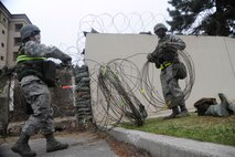 Staff Sergeant Katrina Acab and Senior Airman Holston Lewis, 8th Communications Squadron members, place concertina-wire around a building during an operational readiness exercise at Kunsan Air Base, Republic of Korea, April 23, 2012. Beverly Midnight 12-02 is the last phase of a three-week series of inspections by the Pacific Air Force’s Inspector General Team. U.S. Air Force photo/Staff Sgt. Rasheen A. Douglas)