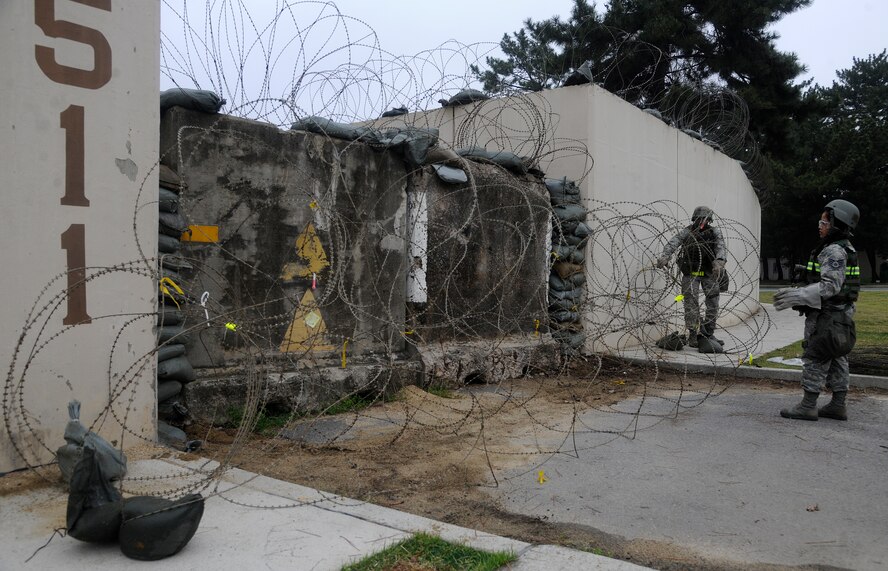 Staff Sergeant Katrina Acab and Senior Airman Holston Lewis, 8th Communications Squadron members, place concertina-wire around a building during an operational readiness exercise at Kunsan Air Base, Republic of Korea, April 23, 2012. Beverly Midnight 12-02 is the last phase of a three-week series of inspections by the Pacific Air Force’s Inspector General Team. (U.S. Air Force photo/Staff Sgt. Rasheen A. Douglas)