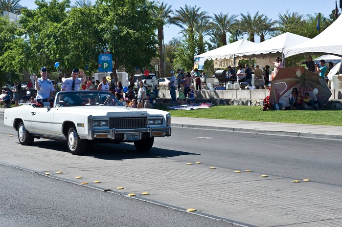 U.S. Air Force Tech. Sgt. Angela Pollard, 99th Medical Operations Squadron NCO in charge of the emergency room, and Senior Airman Tyler Jones, 99th Communications Squadron radio frequency transmitter technician and maintainer, wave to the audience during the Henderson Heritage Parade & Festival April 21, 2012, in Henderson, Nev. As part of their duties as grand marshals, the selected Airmen led the parade procession through the historic Water Street District. (U.S. Air Force photo by Airman 1st Class Christopher Tam)