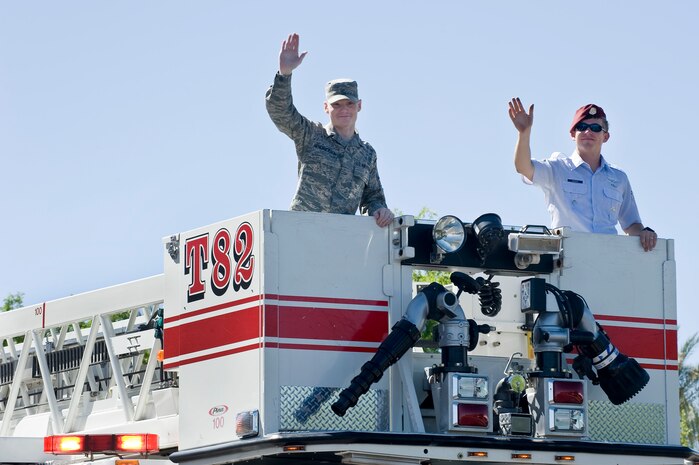 U.S. Air Force Senior Airman Jonah Hendrickson, 42nd Attack Squadron mission intelligences analyst, and Senior Airman Jackson Rogers, 58th Rescue Squadron pararescueman, wave to the  audience during the Henderson Heritage Parade & Festival April 21, 2012, in Henderson, Nev. Five Airmen from Nellis Air Force Bace were selected to be grand marshals of the parade for their exemplary service, extraordinary accolades and dedication to protecting the United States. (U.S. Air Force photo by Airman 1st Class Matthew Lancaster)