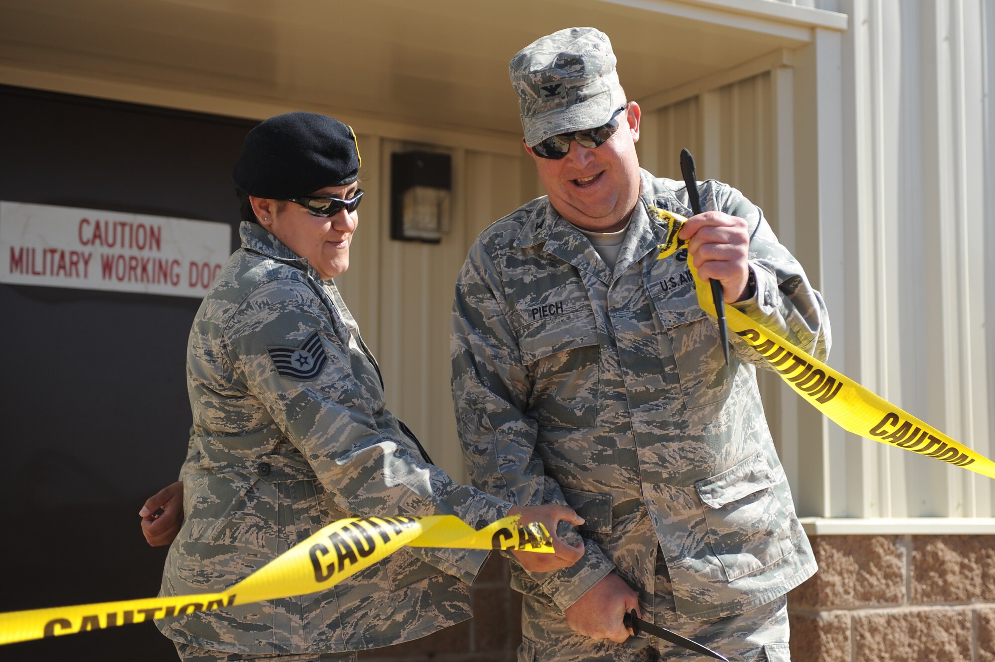 U.S. Air Force Tech. Sgt. Esther Standridge, 27th Special Operations Security Forces Squadron K-9 military working dog handler, and Col. David Piech, 27th Special Operations Mission Support Group commander,  cut the ribbon to unveil the newly constructed military working dog kennels, veterinary facilities and administrative offices at Cannon Air Force Base, N.M., April 23, 2012. Members from the New Mexico State Police Department and former military dog handlers were present for the ribbon cutting ceremony. (U.S. Air Force photo by Airman 1st Class Eboni Reece)
