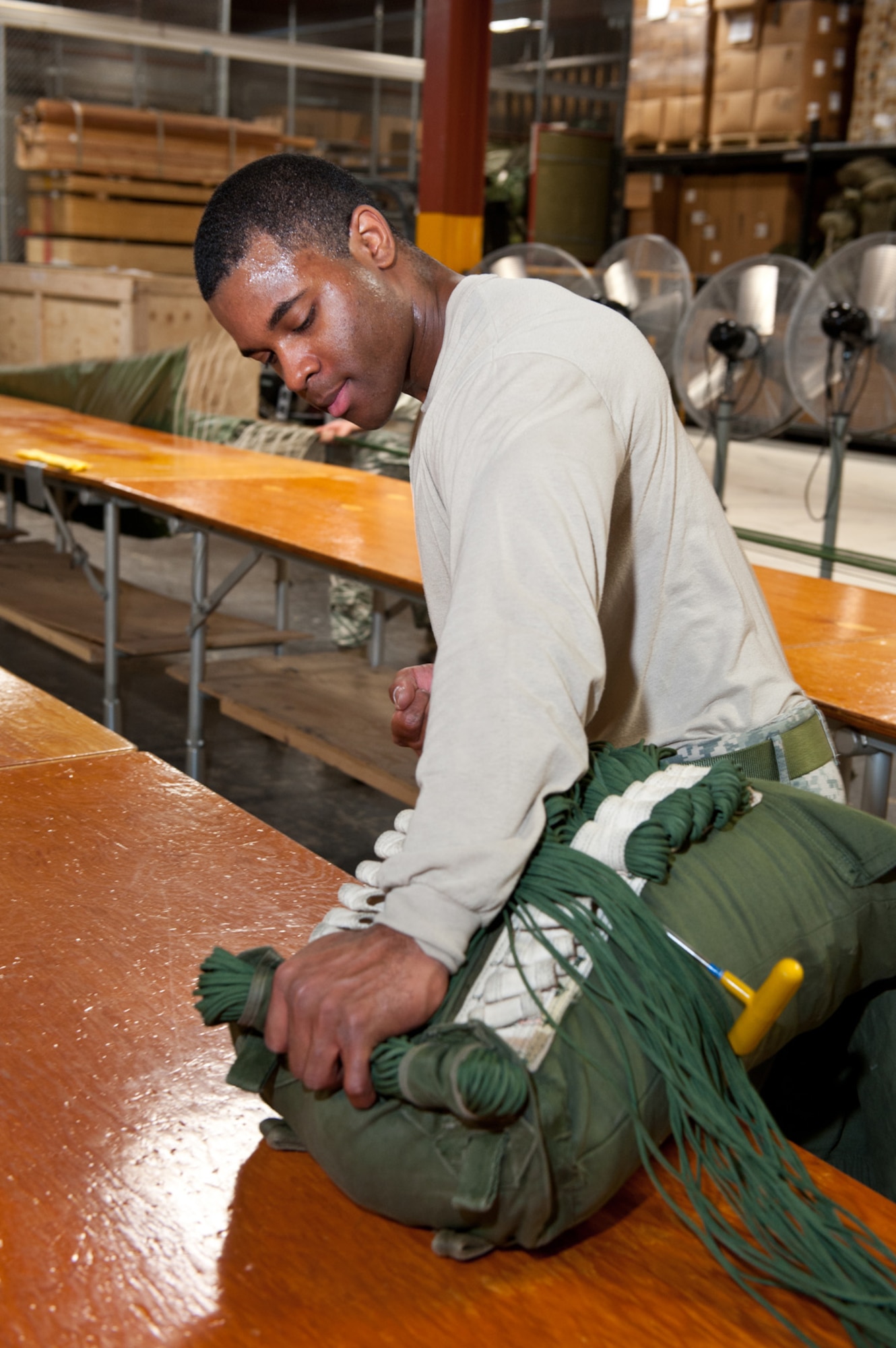 JOINT BASE ELMENDORF-RICHARDSON, Alaska - - Sgt. Rasheen Threatts, Parachute Inspector, 4th Quartermaster Detachment (Airborne), 17th Combat Sustainment Support Battalion, uses specialized tools to pull the lines of the parachute to the deployment bag, April 4. This portion of process is called "stowing the lines." (U.S. Air Force photo/Johnathon Green)