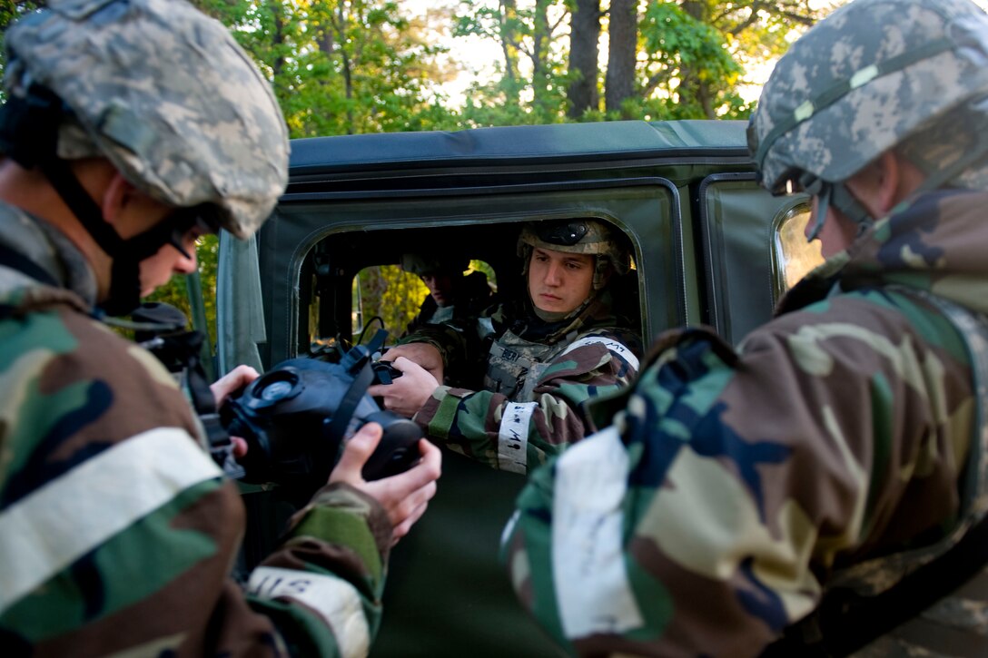 Senior Airman Bradley Biery, 633rd Force Support Squadron patrolmen verifys Airman 1st Class Kyle Dehaan and Jordan Jensen 633rd Security Forces Squadron entry control point guards,  M-50 gas mask's serial numbers, during exercise Coronet White in Raptor Town at Langley Air Force Base, Va. April 20. The Operational Readiness Exercise tests Airmen's abilities to perform self-aid buddy care, Mission Oriented Protective Posture procedures as well as responding approriately to Alarm Conditions. (U.S. Air Force photo by Senior Airman John D. Strong II/Released)