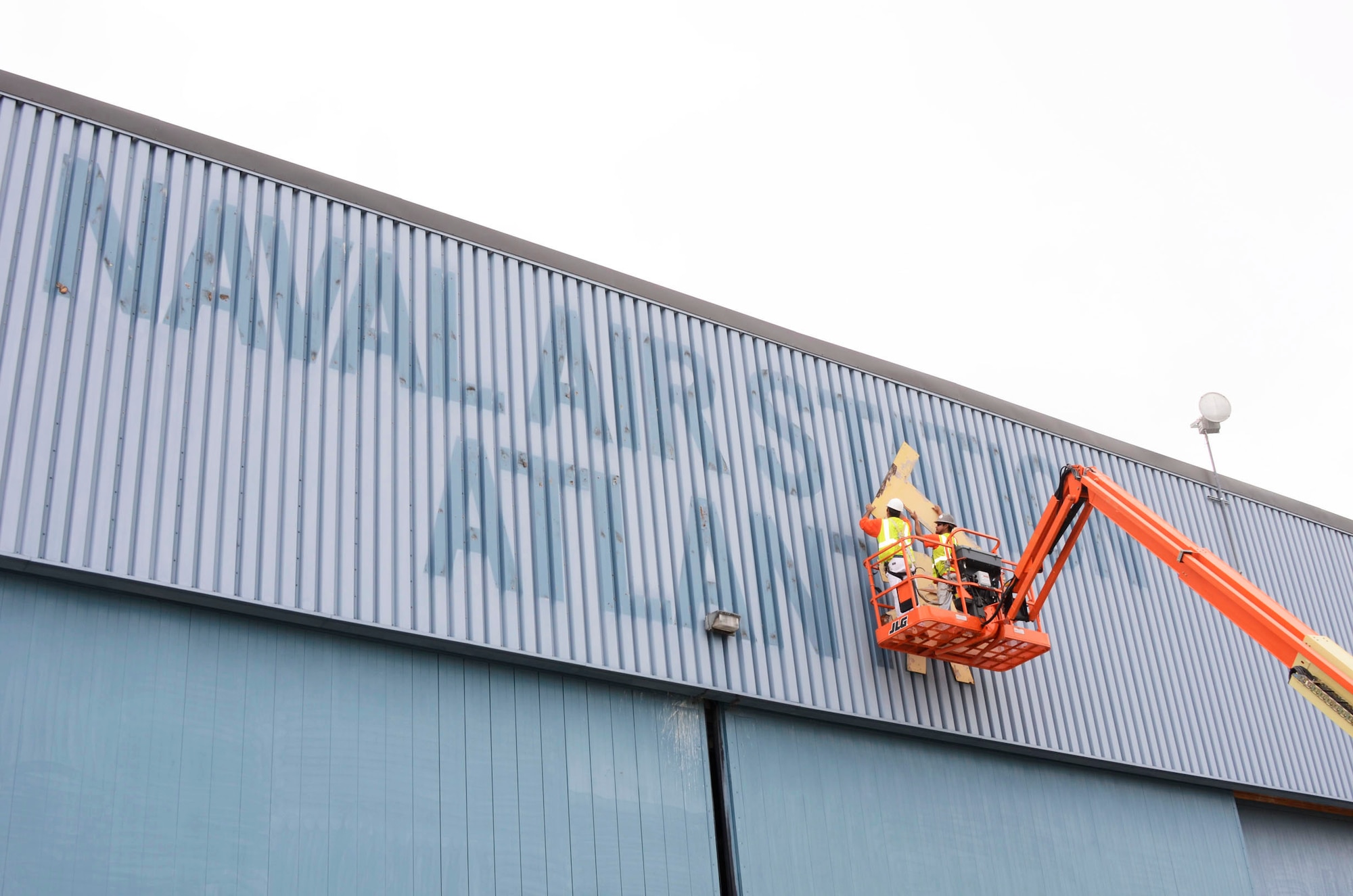 The last of the letters are removed by remodeling work crews exposing the outline of the signage, from Hangar 5, one of the last structures still holding the identity of the former Naval Air Station Atlanta April 17. (U.S. Air Force photo/Don Peek)
