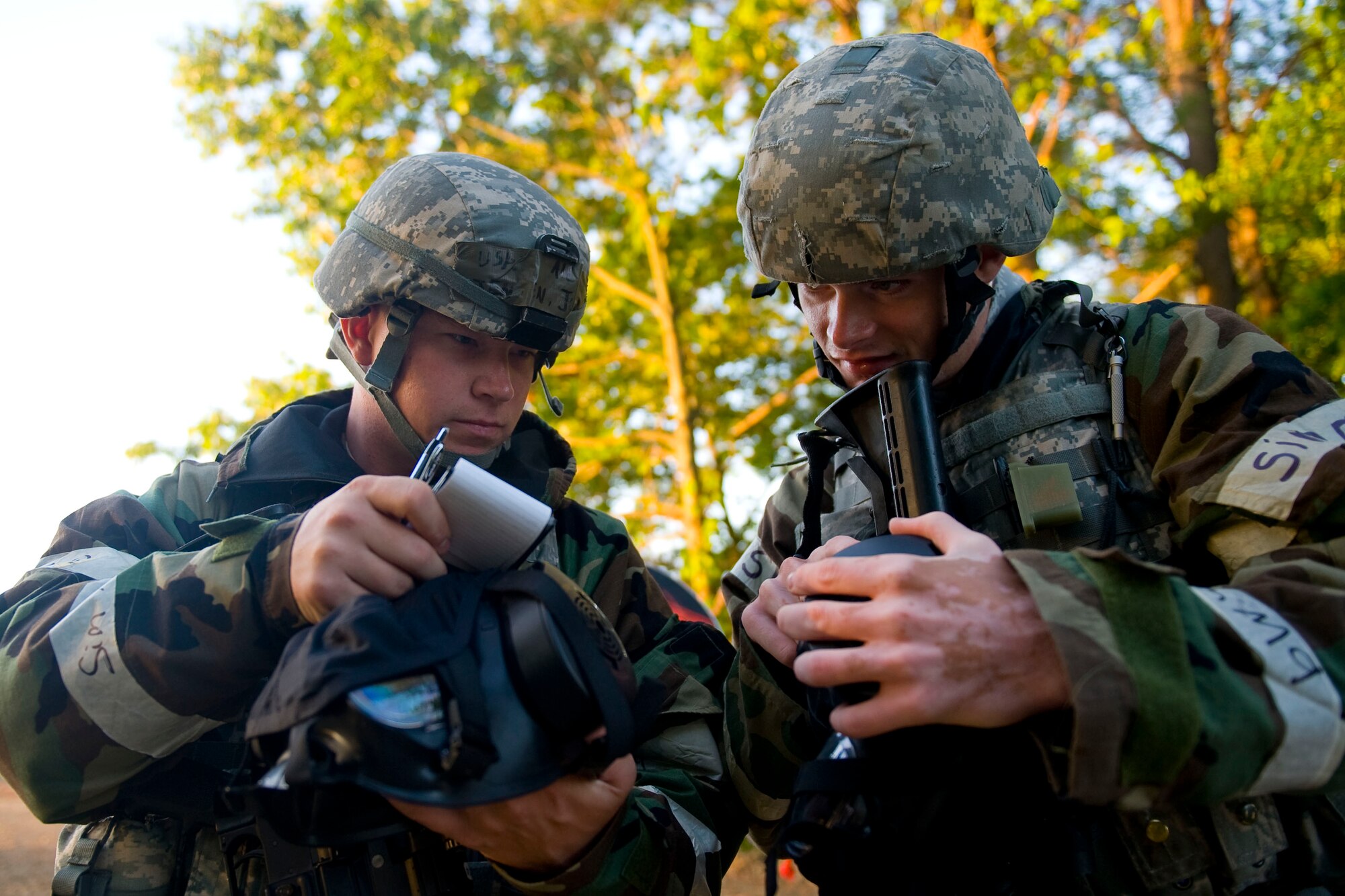 Airman 1st Class Kyle Dehaan and Jordan Jensen 633rd Security Forces Squadron entry control point guards, check their M-50 gas mask's serial numbers during exercise Coronet White at the Raptor Town entry control point at Langley Air Force Base, Va., April 20. The Airmen received a mock scenario radio message saying that certain gas masks were defective . (U.S. Air Force photo by Senior Airman John D. Strong II/Released)