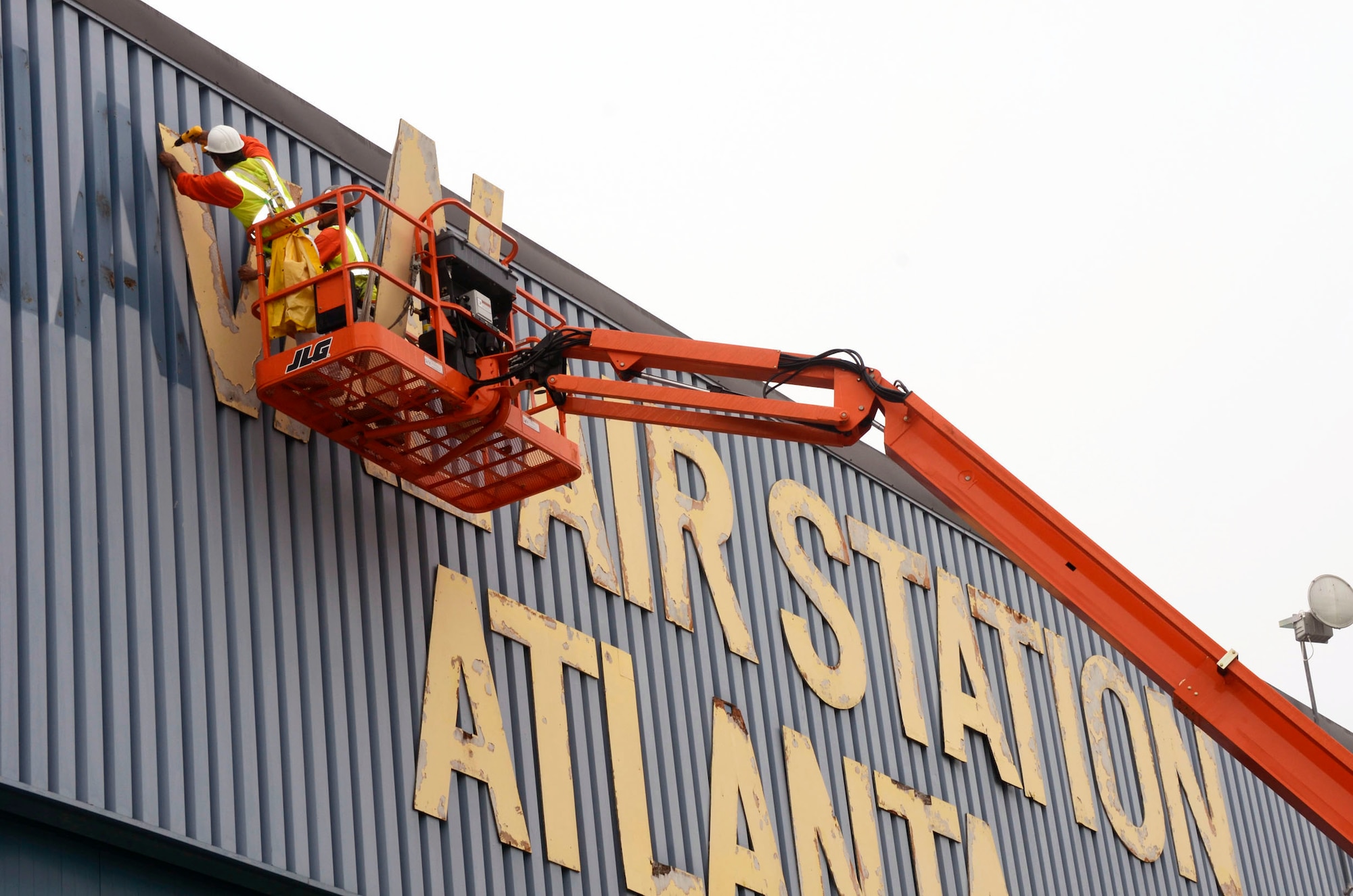 During remodeling work crews remove the signage letter by letter from Hangar 5, one of the last structures still holding the identity of the former Naval Air Station Atlanta April 17. (U.S. Air Force photo/Don Peek)