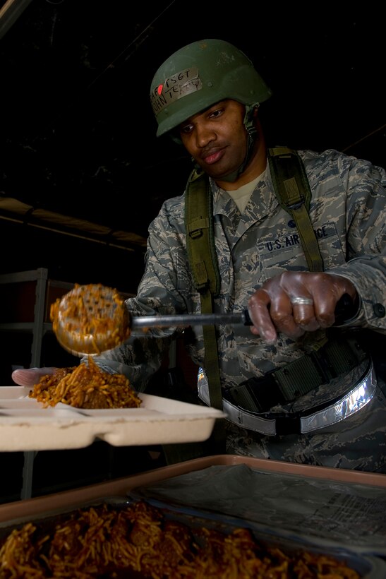 Tech. Sgt. John Terry, 633rd Force Support Squadron NCO in charge of Food Services, serves spaghetti and meatballs to an Airman at the field dining facility during exercise Coronet White in Raptor Town at Langley Air Force Base, Va. April 19. The Operational Readiness Exercise was held to help Langley Airmen to prepare for the upcoming Operational Readiness Inspection. (U.S. Air Force photo by Senior Airman John D. Strong II/Released)