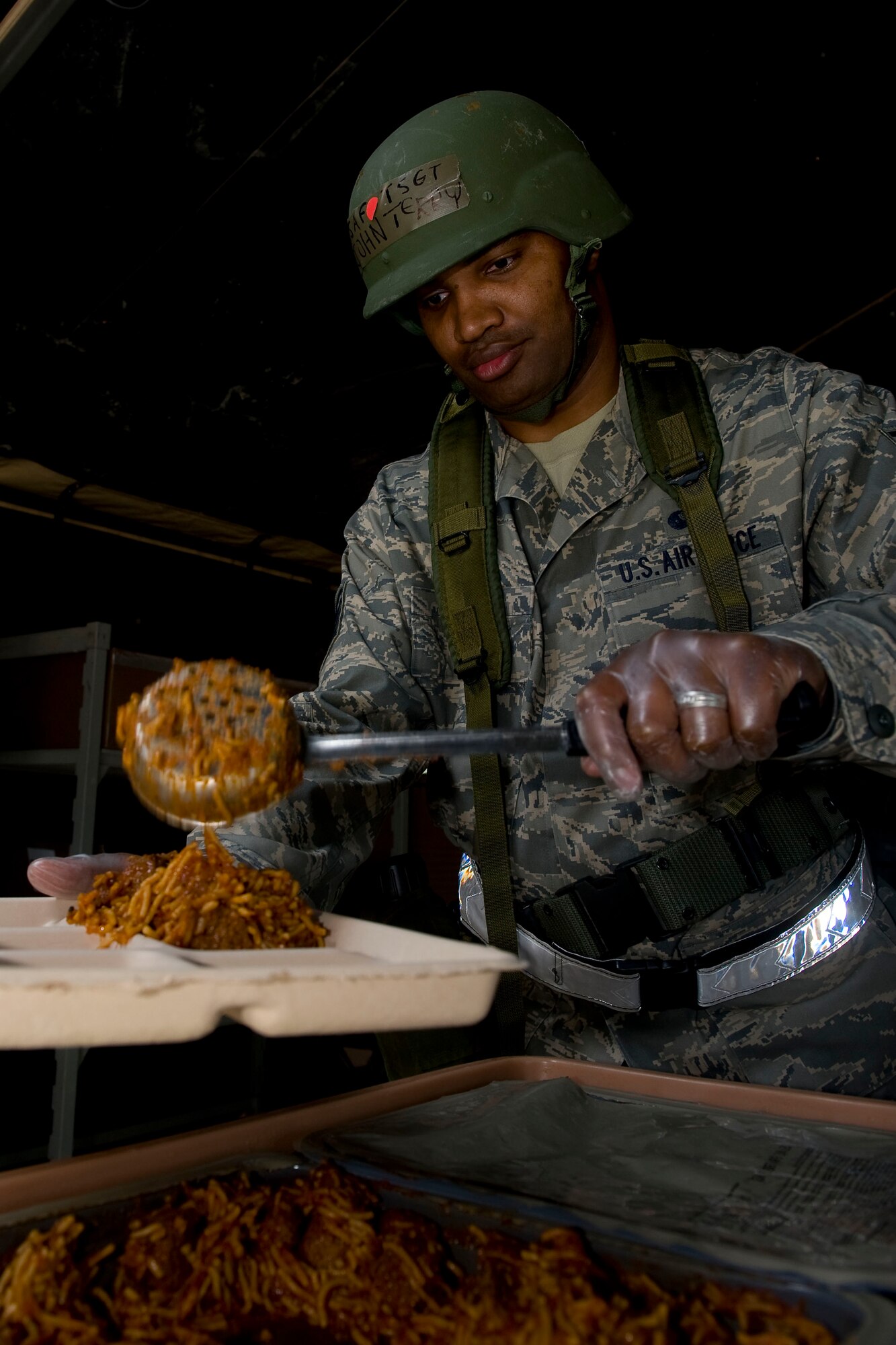 Tech. Sgt. John Terry, 633rd Force Support Squadron NCO in charge of Food Services, serves spaghetti and meatballs to an Airman at the field dining facility during exercise Coronet White in Raptor Town at Langley Air Force Base, Va. April 19. The Operational Readiness Exercise was held to help Langley Airmen to prepare for the upcoming Operational Readiness Inspection. (U.S. Air Force photo by Senior Airman John D. Strong II/Released)