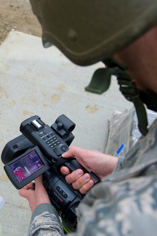 Airman 1st Class Anthony Hetlage, 633rd Air Base Wing Public Affairs broadcaster, records the apprehension of an intruder during exercise Coronet White in Raptor Town at Langley Air Force Base, Va., April 19. The Phase I and Phase II exercise was held to validate the full spectrum of Langley's deployment operations. (U.S. Air Force photo by Senior Airman John D. Strong II/Released)
