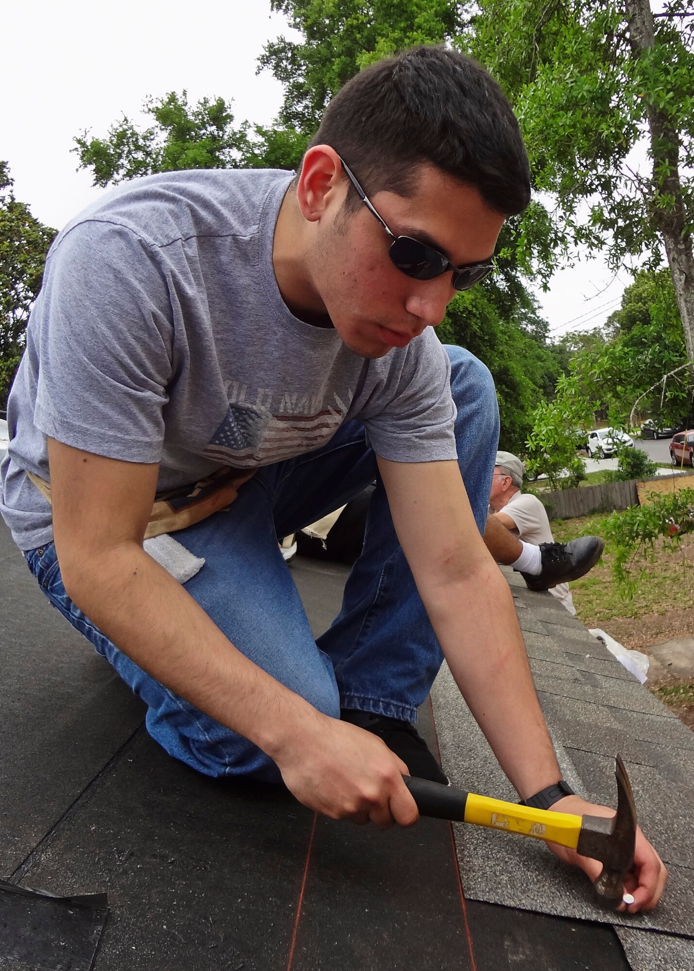Airman 1st Class Damian De Leon, of the 46th Aircraft Maintenance Squadron, nails a shingle into place with a hammer at a Habitat for Humanity event in Fort Walton Beach, Fla., April 21.  More than 10 46th AMXS members worked four hours putting shingles up on a newly built home.  Maintenance squadron volunteers participate in Habitat for Humanity projects two to three times per month.  (Courtesy photo/Senior Airman Alexander Blench)