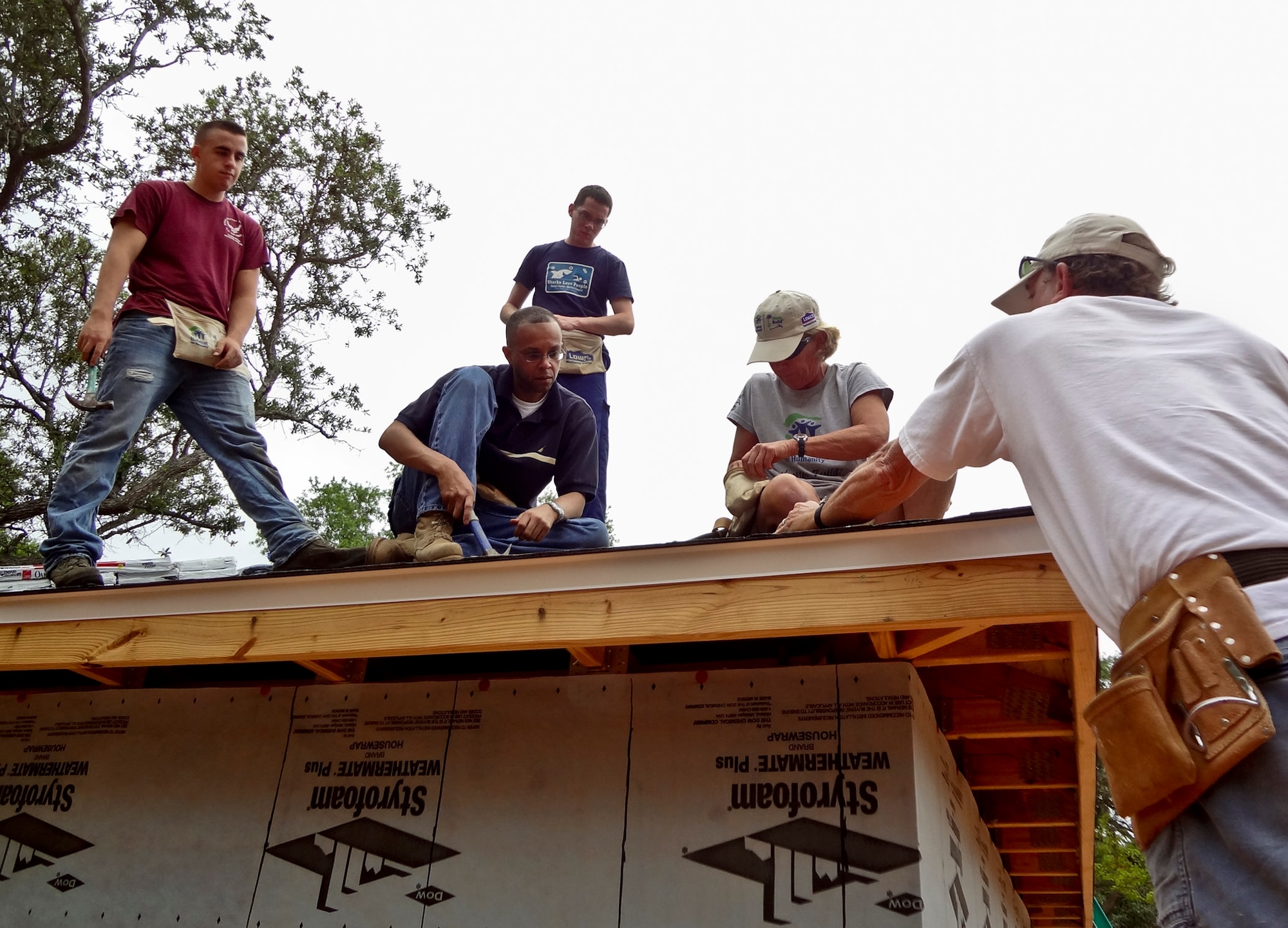 Airman 1st Class Chris Caputo, Capt. Yogi Lebby and Airman 1st Class Aaron DeForge, of the 46th Aircraft Maintenance Squadron, talk with Habitat for Humanity coordinators while shingling the roof of a newly built home in Fort Walton Beach, Fla., April 21.  More than 10 46th AMXS members worked four hours on the roof of the home.  Maintenance squadron volunteers participate in Habitat for Humanity projects two to three times per month.  (Courtesy photo/Senior Airman Alexander Blench)
