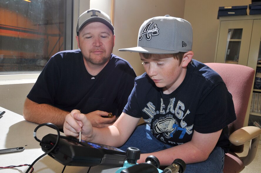 Colt Seals, a student at North Middle School in Franklin County, calibrates a pressure transducer with assistance from father, Tracy Seals, an Aerospace Testing Alliance (ATA) instrument technician in the Test Assets and Support Department at Arnold Engineering Development Center (AEDC). Seals was visiting the center for Job Shadow Day April 17. (Photo by Rick Goodfriend)