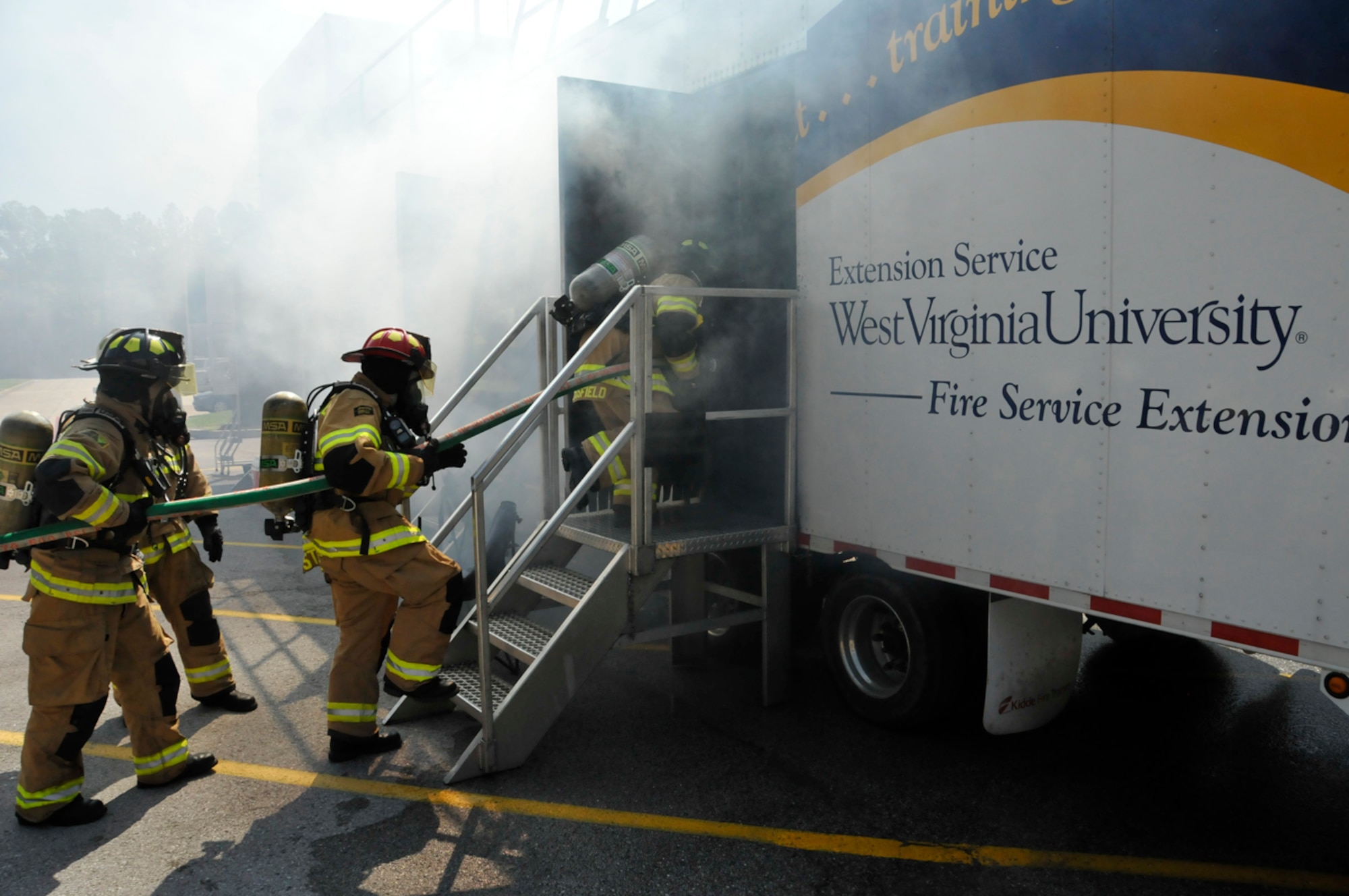 AEDC firefighters prepare to enter a smoke-filled room and put out a simulated kitchen fire March 27. The training unit from West Virginia University can simulate fires on multiple floors and uses theatrical smoke. (Photo by Rick Goodfriend)