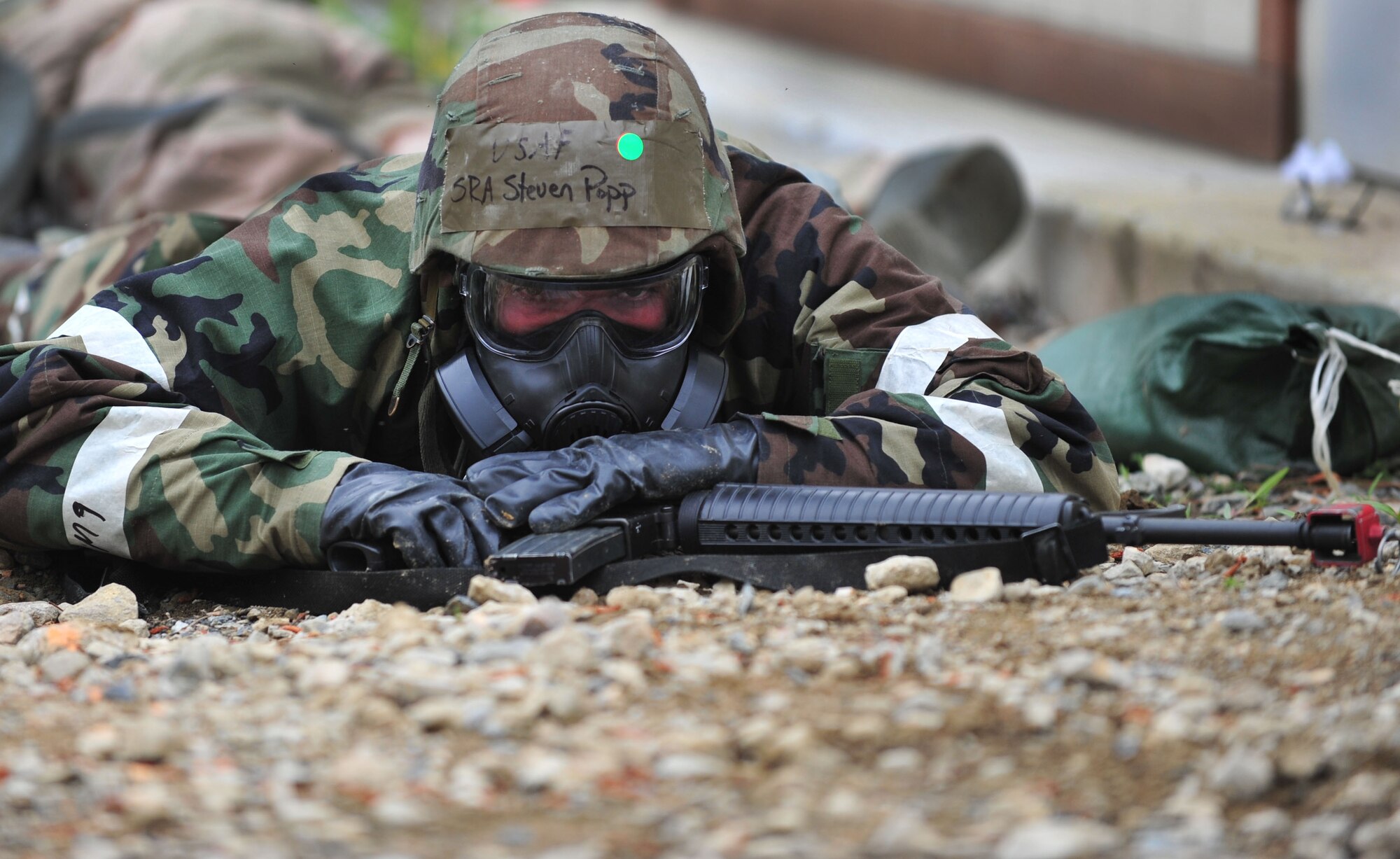 U.S. Air Force Senior Airman Steven Popp, 633rd Civil Engineer Squadron entry control point monitor, covers down after a simulated chemical attack during a Phase II Operational Readiness Exercise at Langley Air Force Base, Va., April 20, 2012. Throughout the ORE, Airmen were required to perform both their jobs and additional duties while wearing mission oriented protective posture gear. (U.S. Air Force photo by Senior Airman Jarad A. Denton/Released)