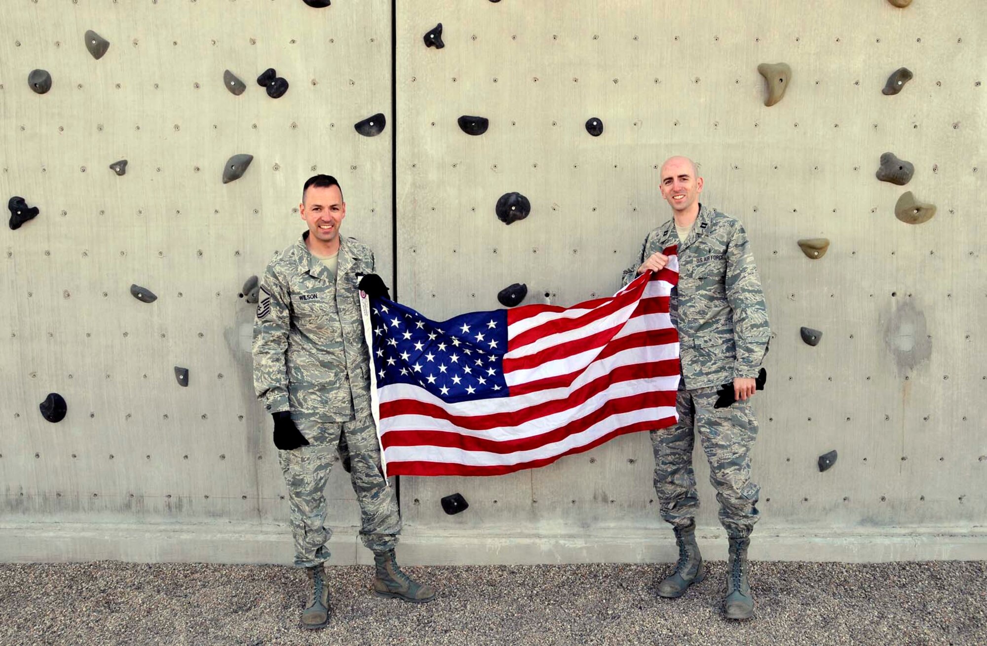 Master Sgt. Curtis Wilson, left, and his brother, Capt. Heath Wilson, display the flag used during an April 2012 reenlistment ceremony that had Sergeant Wilson and his brother rapelling from a wall at the U.S. Air Force Pararescue School at Kirtland Air Force Base, N.M. Sergeant Wilson has carried the flag during several deployments over his career and plans to present it to his brother when he retires. Sergeant Wilson is assigned to Air Force Operational Test and Evaluation Center Headquarters at Kirtland and Captain Wilson is assigned to the 99th Medical Group at Nellis AFB, Nev. (Photo by George Diamond).