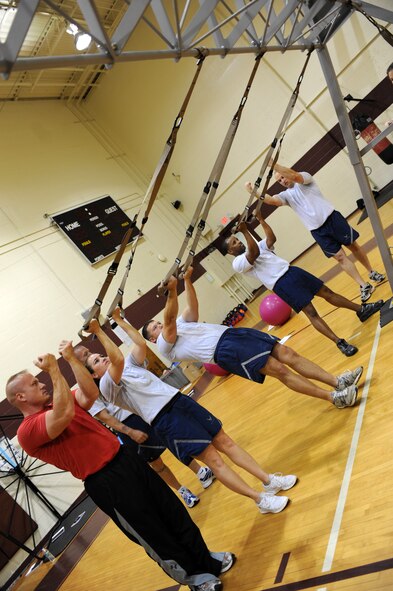 Physical training leaders from the 4th Fighter Wing work together to practice performing bicep curls during a Total Body Resistance Exercise and Suspension Training course at the base fitness center on Seymour Johnson Air Force Base, N.C., April 19, 2012. The TRX equipment consists of two nylon straps, handles and foot cradles.  It can be suspended from any sturdy beam to include doors, trees and light poles. (U.S. Air Force photo/Staff Sgt. Courtney Richardson/Released)