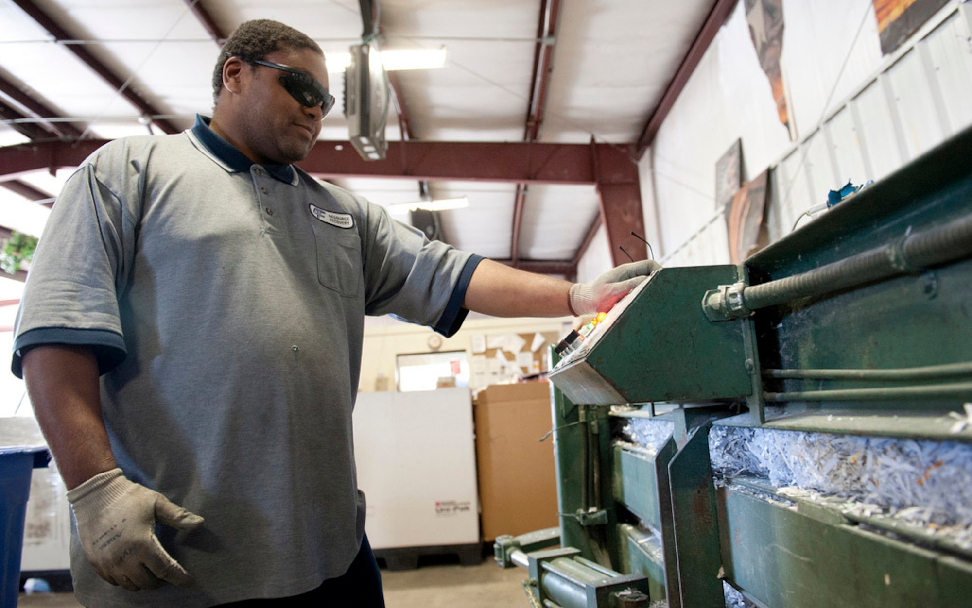 Keith Sanford, of the Joint Base Recycling Center here, operates a paper compressor machine used for fine shredding of private, sensitive and classified information. The Joint Base Recycling Center recycled 13 tons of shredded paper in 2011. Recycling materials helps reduce the amount of pollution caused by waste. (U.S. Air Force Photo by Russ Meseroll/Released)
