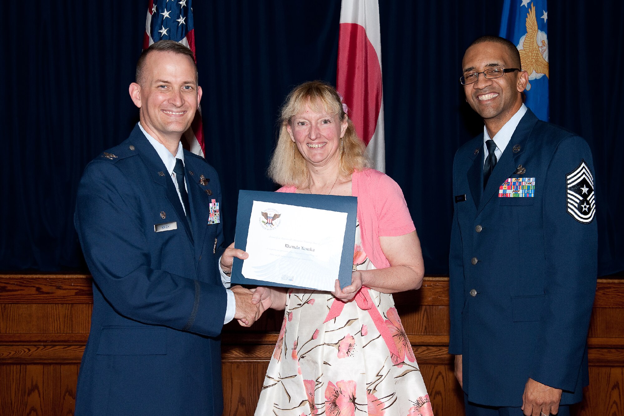 YOKOTA AIR BASE, Japan -- Rhonda Tezuka (center) receives the Presidential Volunteer Service Gold Awards from Col. Bill Knight (left), 374th Airlift Wing commander, and Command Chief Master Sgt. Ronald Draper (right), 374th Airlift Wing, during Yokota's Annual Volunteer Recognition Ceremony at Yokota Air Base, Japan, April 19, 2012. The Presidential Volunteer Service Award recognizes individuals and groups for their dedicated service over the past year and for their cumulative lifetime volunteer service. The gold award winners have provided and documented over 500 hours of volunteer service in 2011. (U.S. Air Force photo/Osakabe Yasuo)