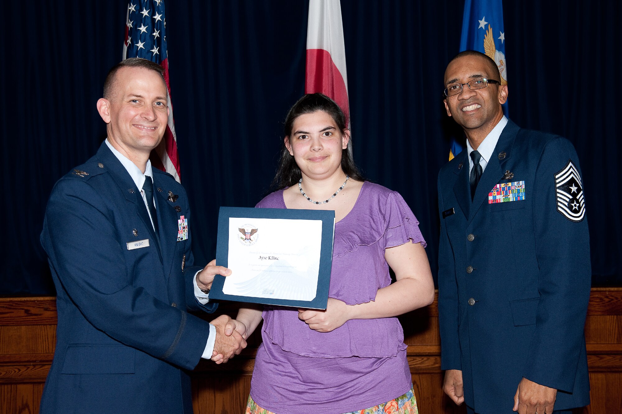 YOKOTA AIR BASE, Japan -- Ayse Kilinc (center) receives the Presidential Volunteer Service Gold Awards from Col. Bill Knight (left), 374th Airlift Wing commander, and Command Chief Master Sgt. Ronald Draper (right), 374th Airlift Wing, during Yokota's Annual Volunteer Recognition Ceremony at Yokota Air Base, Japan, April 19, 2012. The Presidential Volunteer Service Award recognizes individuals and groups for their dedicated service over the past year and for their cumulative lifetime volunteer service. The gold award winners have provided and documented over 500 hours of volunteer service in 2011. (U.S. Air Force photo/Osakabe Yasuo)