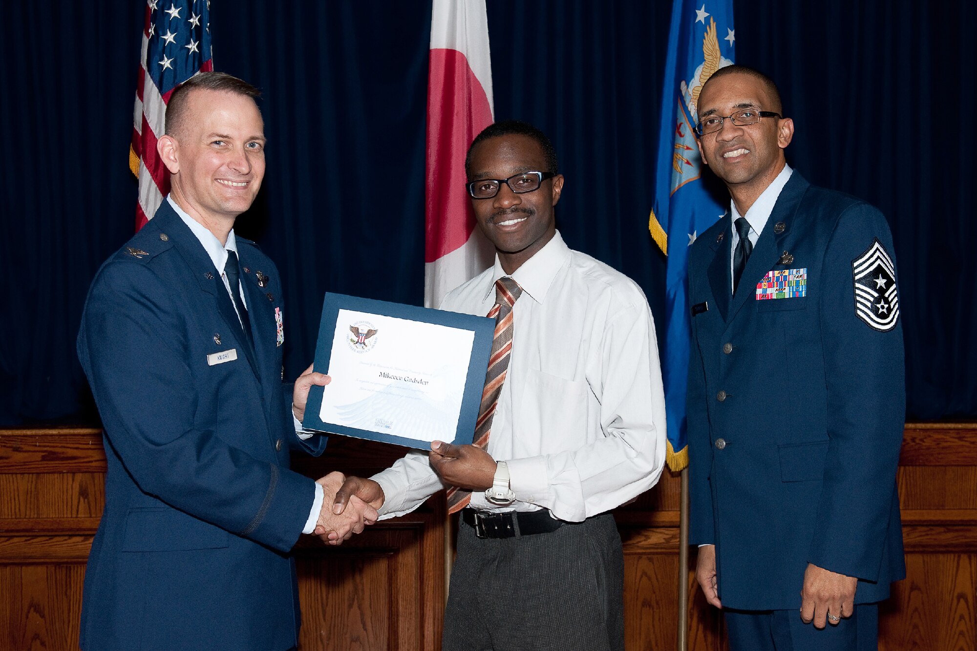 YOKOTA AIR BASE, Japan -- Mikeece Gadsden (center) receives the Presidential Volunteer Service Gold Awards from Col. Bill Knight (left), 374th Airlift Wing commander, and Command Chief Master Sgt. Ronald Draper (right), 374th Airlift Wing, during Yokota's Annual Volunteer Recognition Ceremony at Yokota Air Base, Japan, April 19, 2012. The Presidential Volunteer Service Award recognizes individuals and groups for their dedicated service over the past year and for their cumulative lifetime volunteer service. The gold award winners have provided and documented over 500 hours of volunteer service in 2011. (U.S. Air Force photo/Osakabe Yasuo)