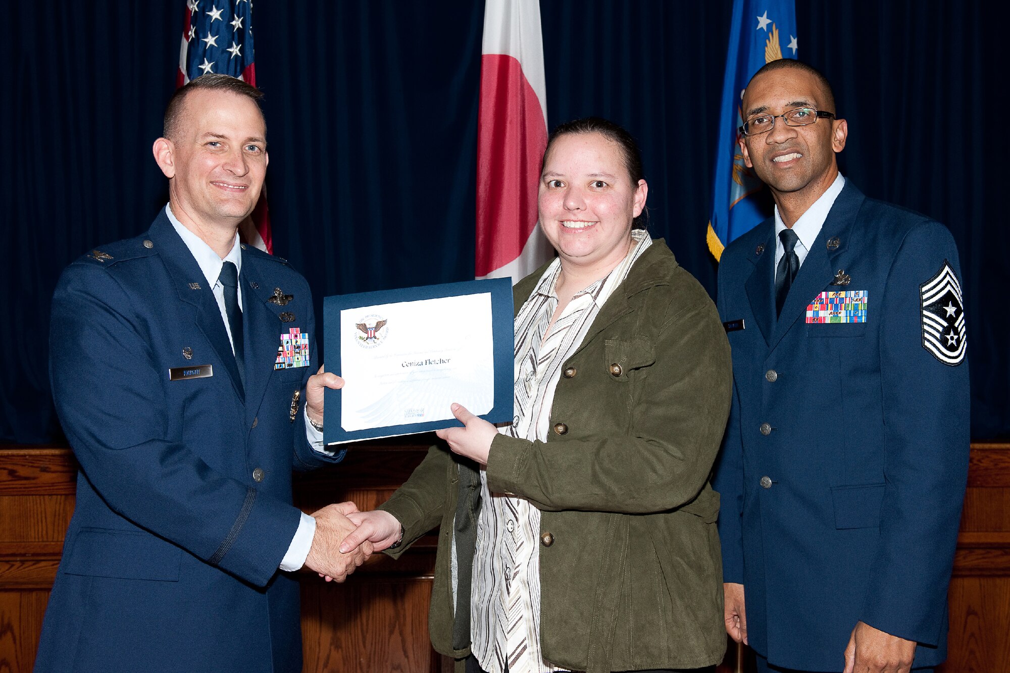 YOKOTA AIR BASE, Japan -- Ceniza Fletcher (center) receives the Presidential Volunteer Service Gold Awards from Col. Bill Knight (left), 374th Airlift Wing commander, and Command Chief Master Sgt. Ronald Draper (right), 374th Airlift Wing, during Yokota's Annual Volunteer Recognition Ceremony at Yokota Air Base, Japan, April 19, 2012. The Presidential Volunteer Service Award recognizes individuals and groups for their dedicated service over the past year and for their cumulative lifetime volunteer service. The gold award winners have provided and documented over 500 hours of volunteer service in 2011. (U.S. Air Force photo/Osakabe Yasuo)