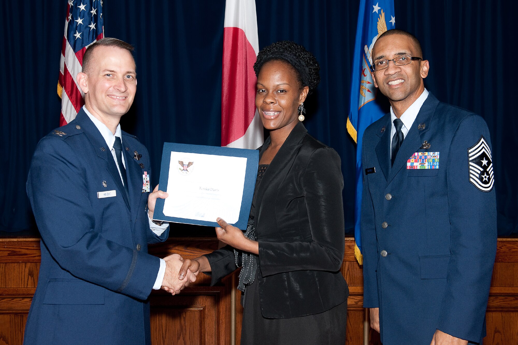YOKOTA AIR BASE, Japan -- Tenika Davis (center) receives the Presidential Volunteer Service Gold Awards from Col. Bill Knight (left), 374th Airlift Wing commander, and Command Chief Master Sgt. Ronald Draper (right), 374th Airlift Wing, during Yokota's Annual Volunteer Recognition Ceremony at Yokota Air Base, Japan, April 19, 2012. The Presidential Volunteer Service Award recognizes individuals and groups for their dedicated service over the past year and for their cumulative lifetime volunteer service. The gold award winners have provided and documented over 500 hours of volunteer service in 2011. (U.S. Air Force photo/Osakabe Yasuo)