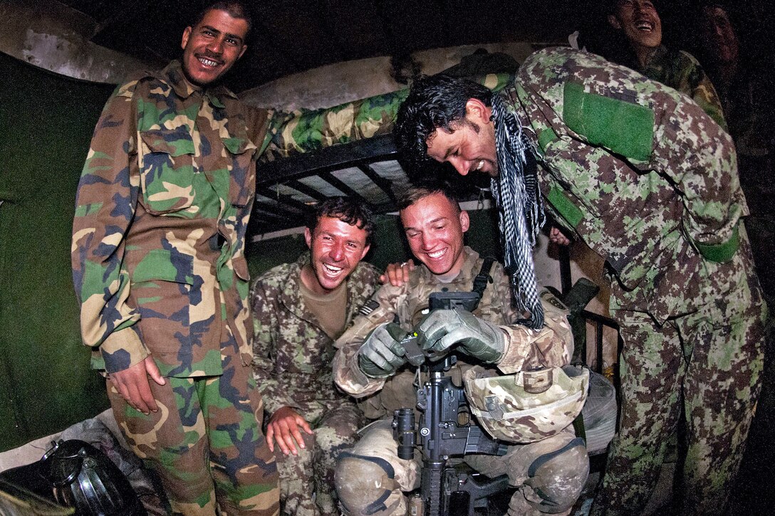 U.S. Army Spc. Jason Schmid shares photos with Afghan soldiers at their post along Highway 1 in Afghanistan's southern Ghazni province, April 20, 2012. Schmid, an infantryman, is assigned to the 82nd Airborne Division’s 2nd Battalion, 504th Parachute Infantry Regiment, 1st Brigade Combat Team.