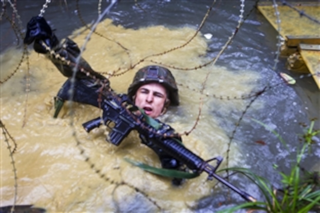 A U.S. Marine crawls through a watery ditch and under concertina wire during a jungle endurance course on Camp Gonsalves, Okinawa, April 20, 2012. After completing a two-week training evolution at the Jungle Warfare Training Center, the Marines took the four-mile-long course through the Okinawan jungle, using rappelling, rope-crossing and other skills they learned. 