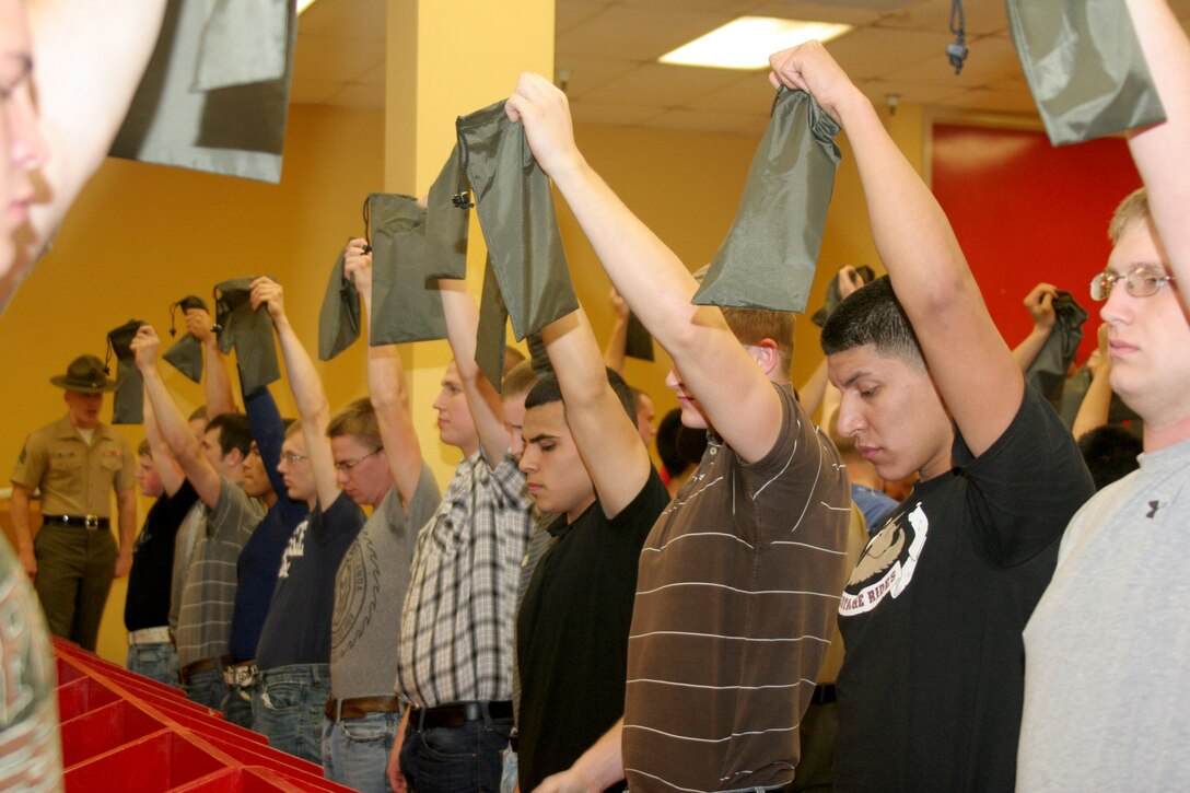 Recruits hold up green-money valuable bag that is issued to them in the contraband room during receiving April 23 aboard Marine Corps Recruit Depot San Diego. Recruits are issued a 'war bag' which consist of basic gear that the recruits will utilize throughout recruit training.